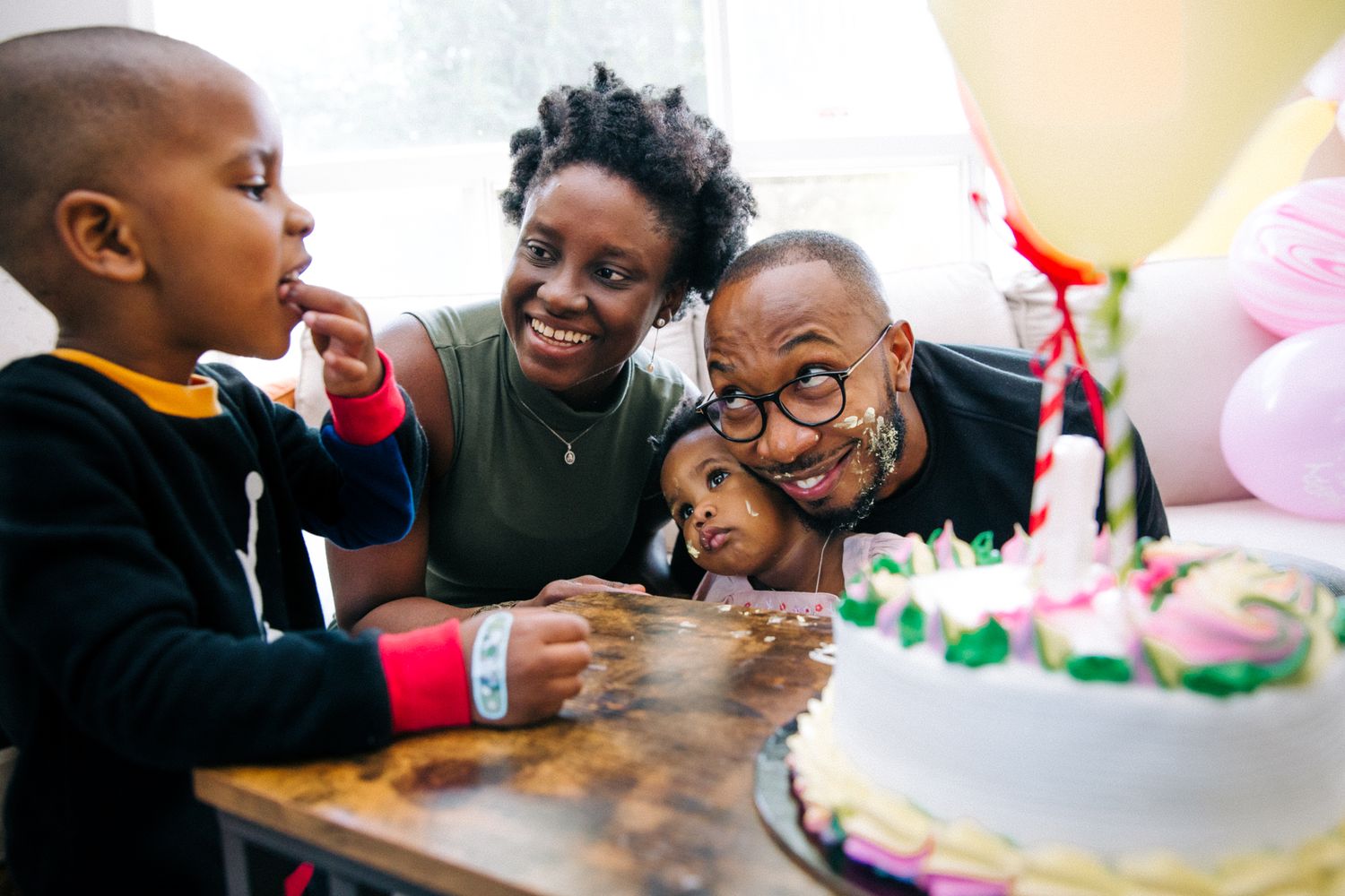 A joyful moment at a birthday party with a festive cake and balloons.