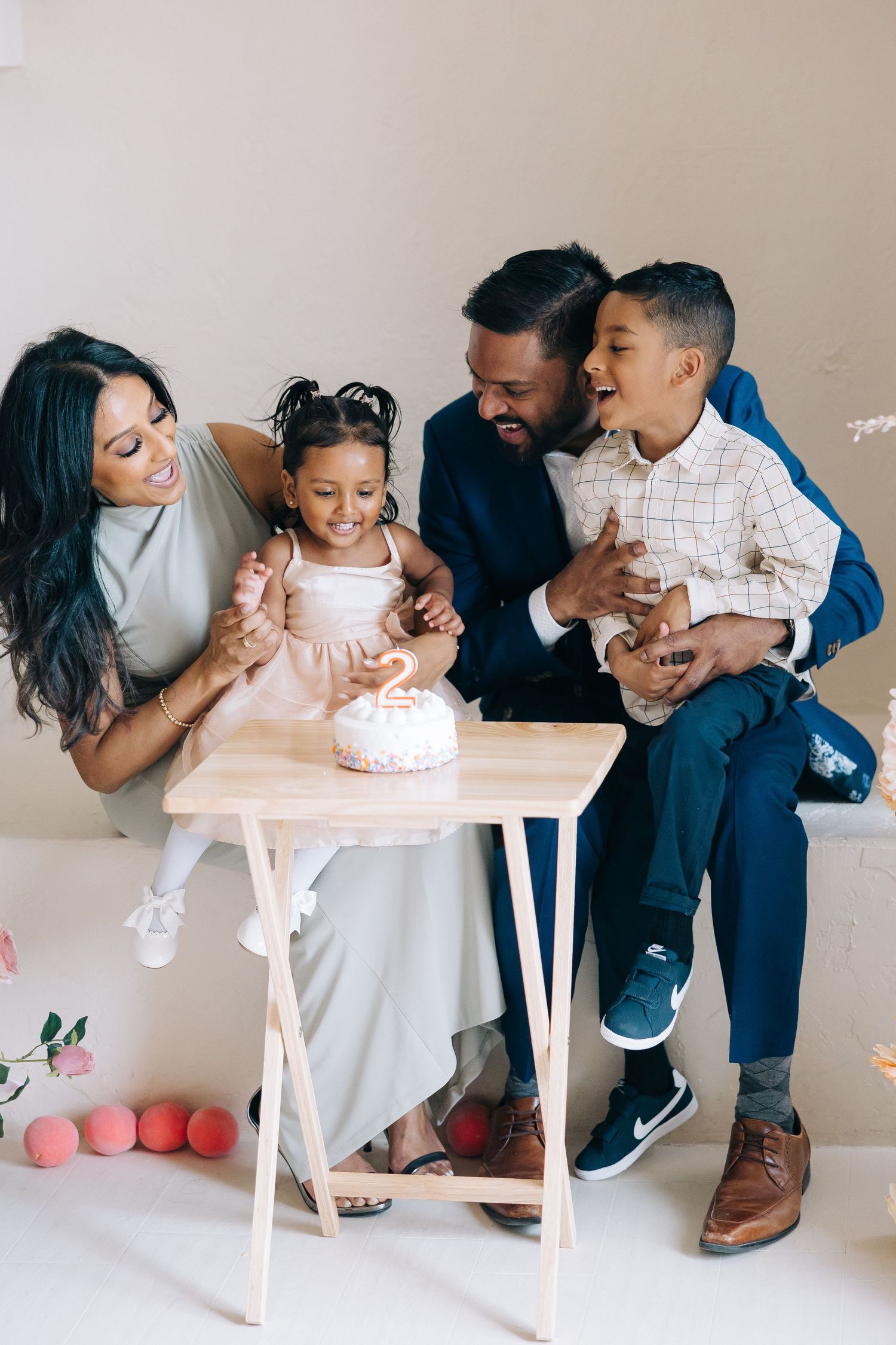 Happy family gathered around a small white cake on a table during a celebration.