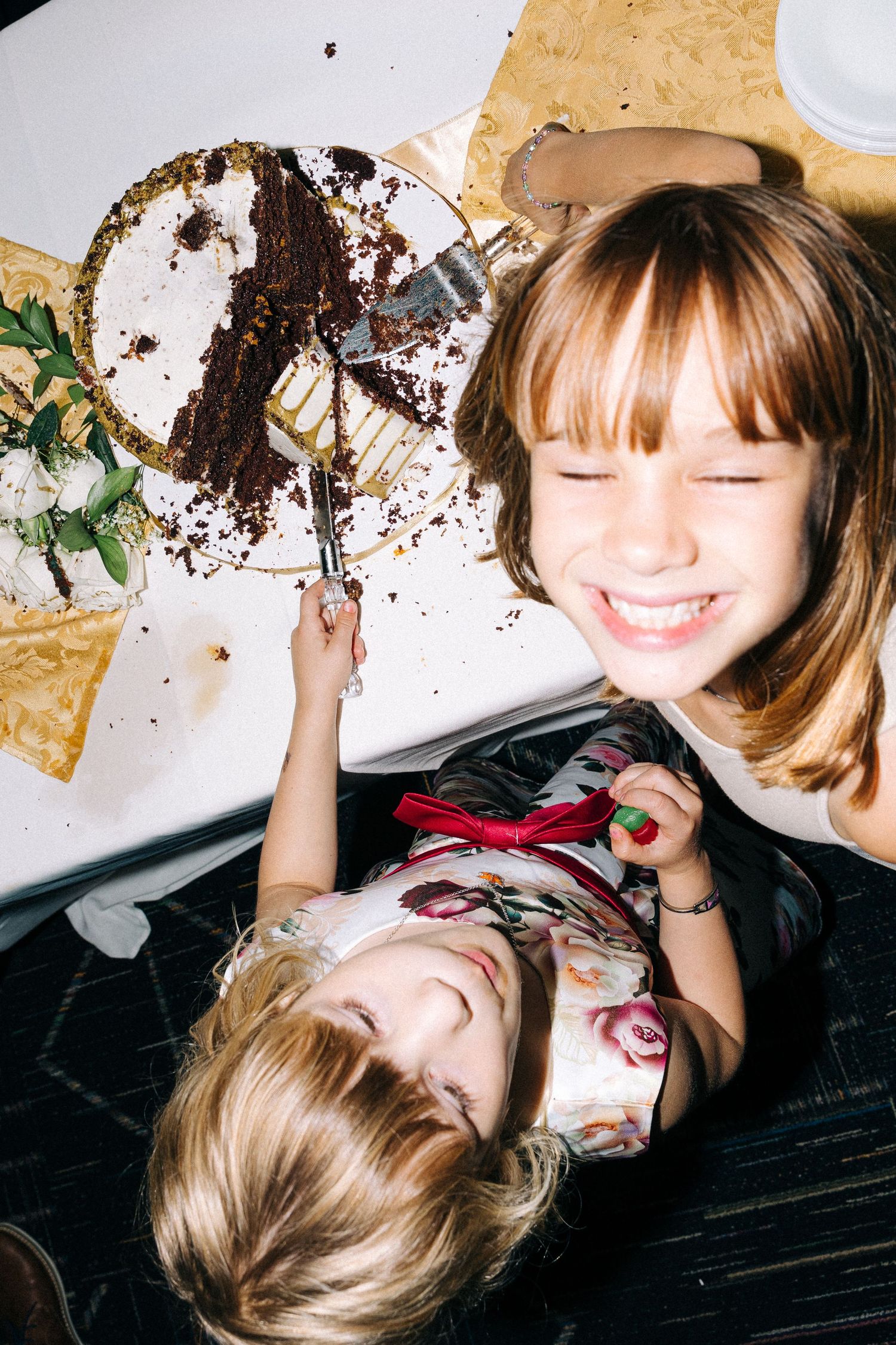 Two children laughing while playing with a messy chocolate cake.