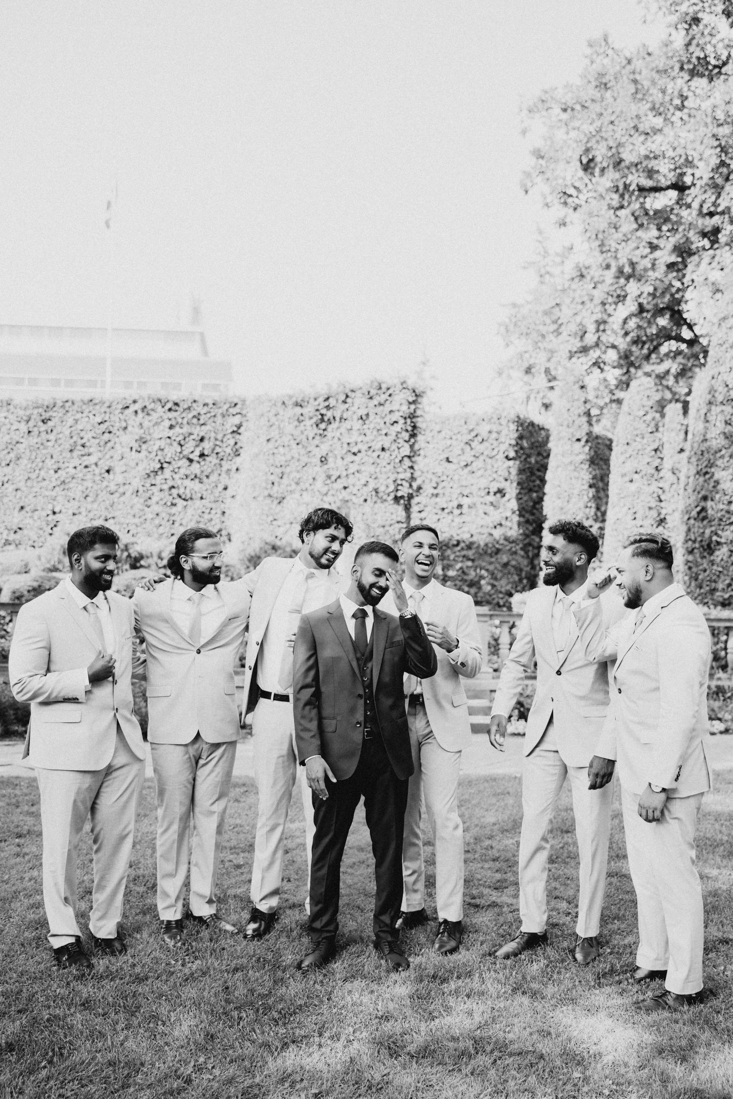 Black and white photo of groomsmen in light suits gathered outdoors.