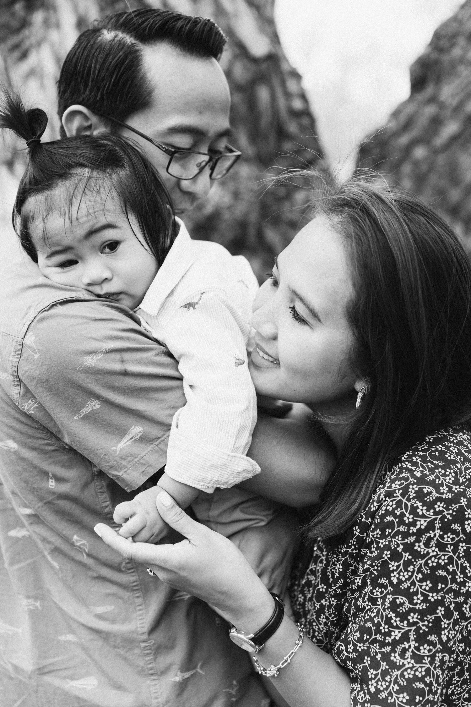 Family sharing tender embrace with young child outdoors in black and white portrait.