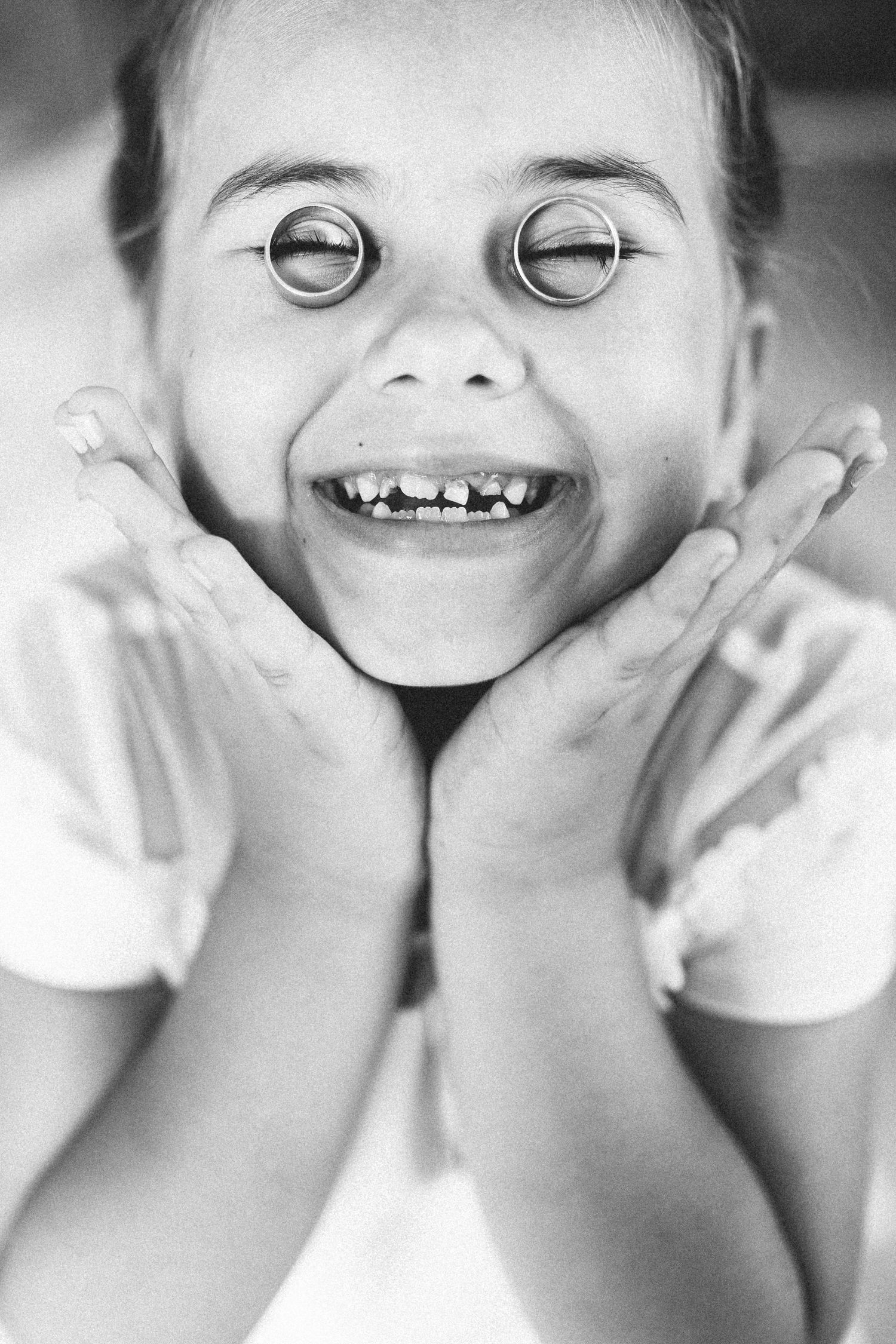 Black and white portrait of a child with a big smile and crossed eyes making a playful silly face.