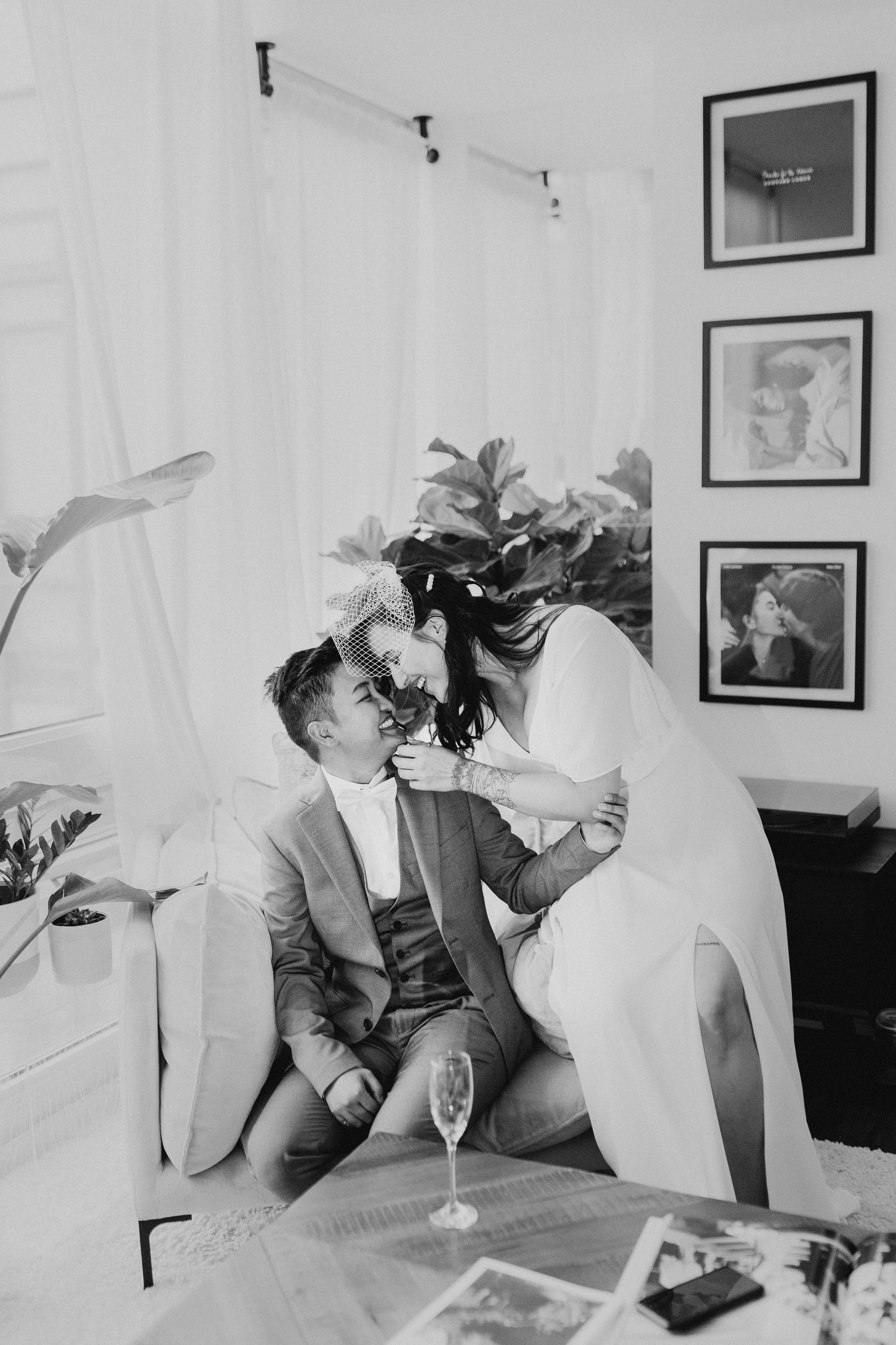 Black and white photo of a wedding couple sharing a playful moment with flowers.