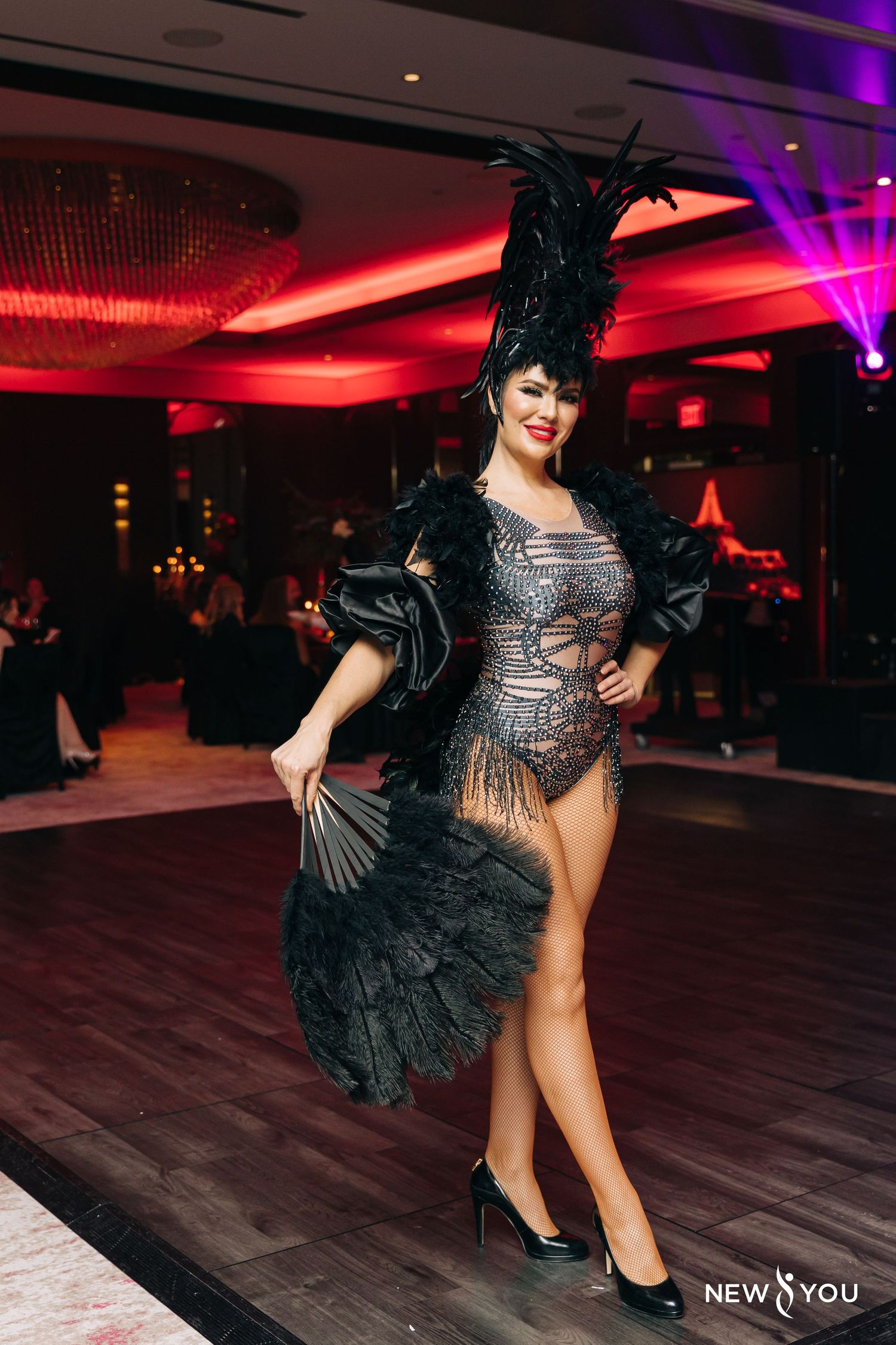 Performer in vintage-style cabaret costume with feathers and sequins on dance floor.