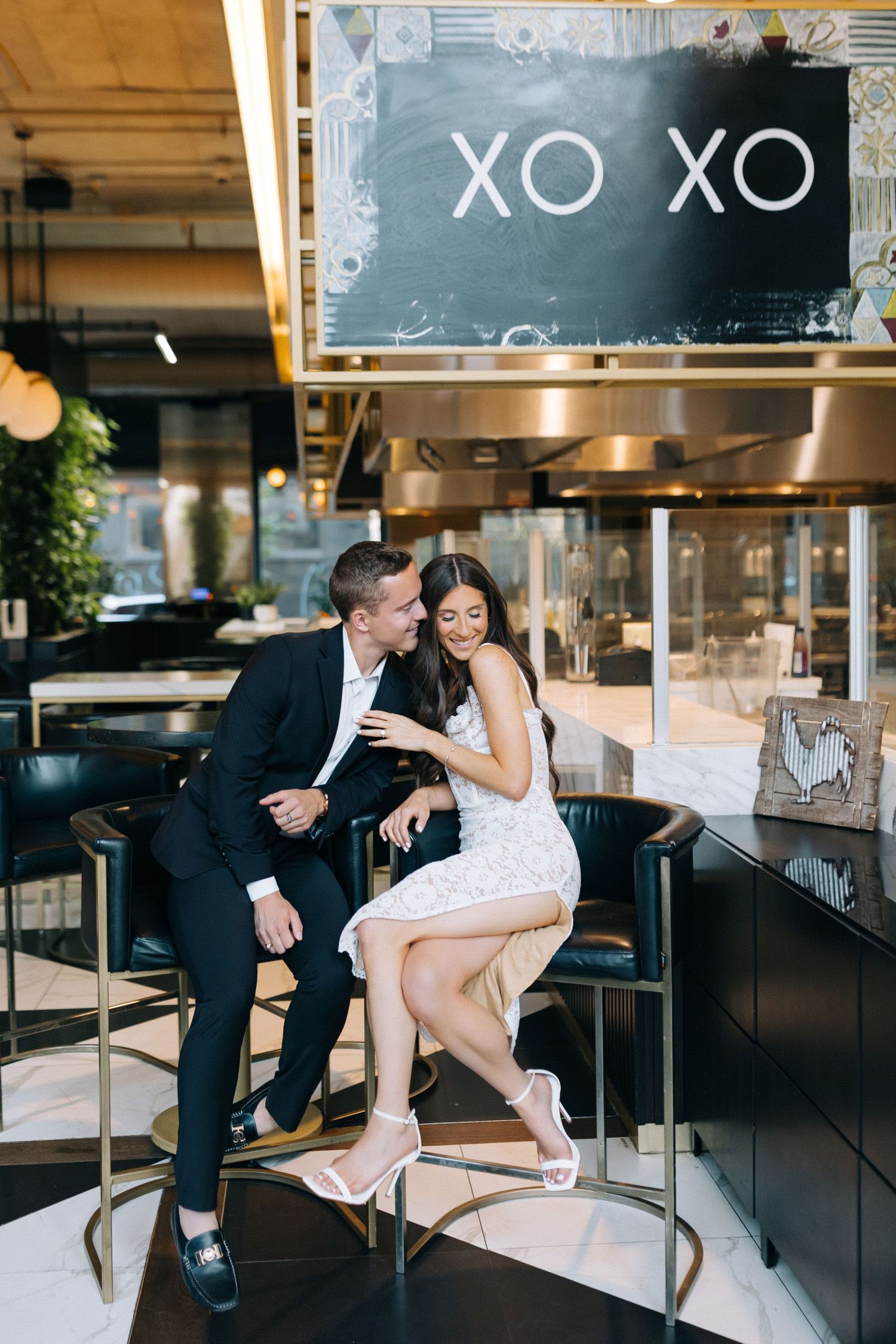 Couple shares romantic moment at bar under XO XO sign.