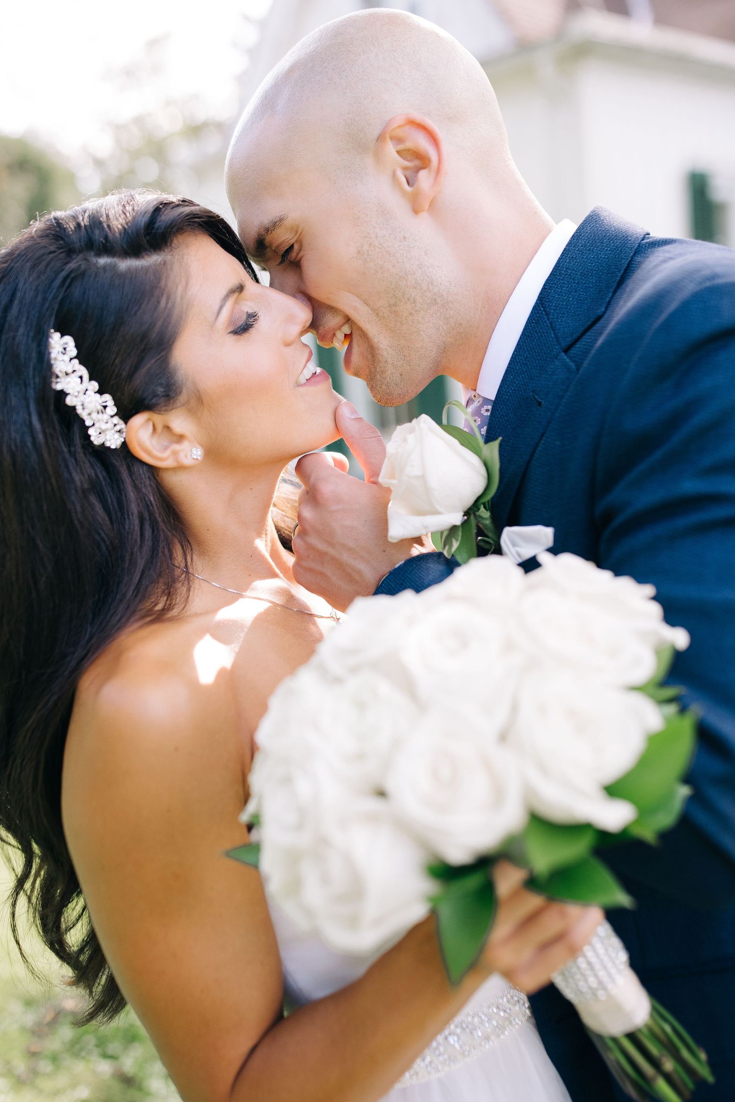 A romantic wedding moment between newlyweds as they embrace while the bride holds a white rose bouquet.