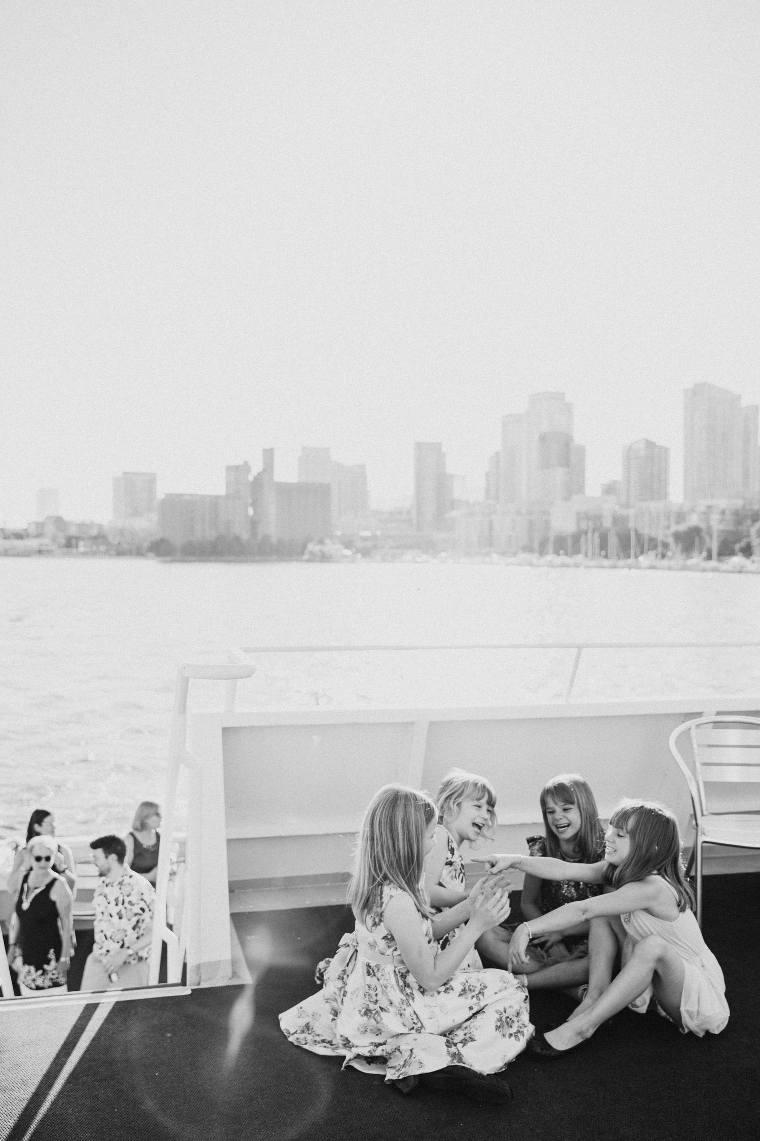 People gather on a boat deck with a cityscape visible in the background.
