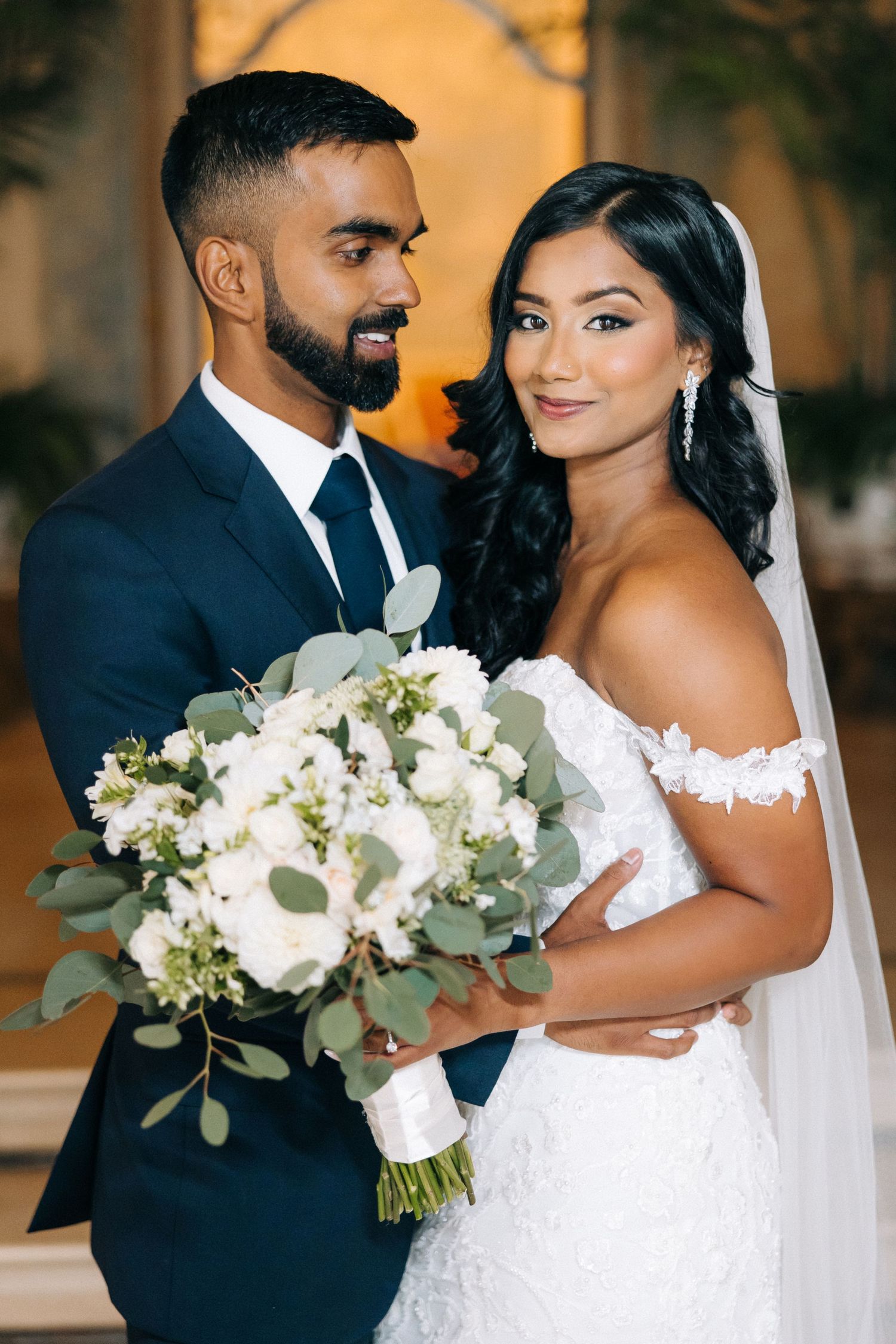 Elegant wedding portrait with beautiful white bouquet and classic navy suit.