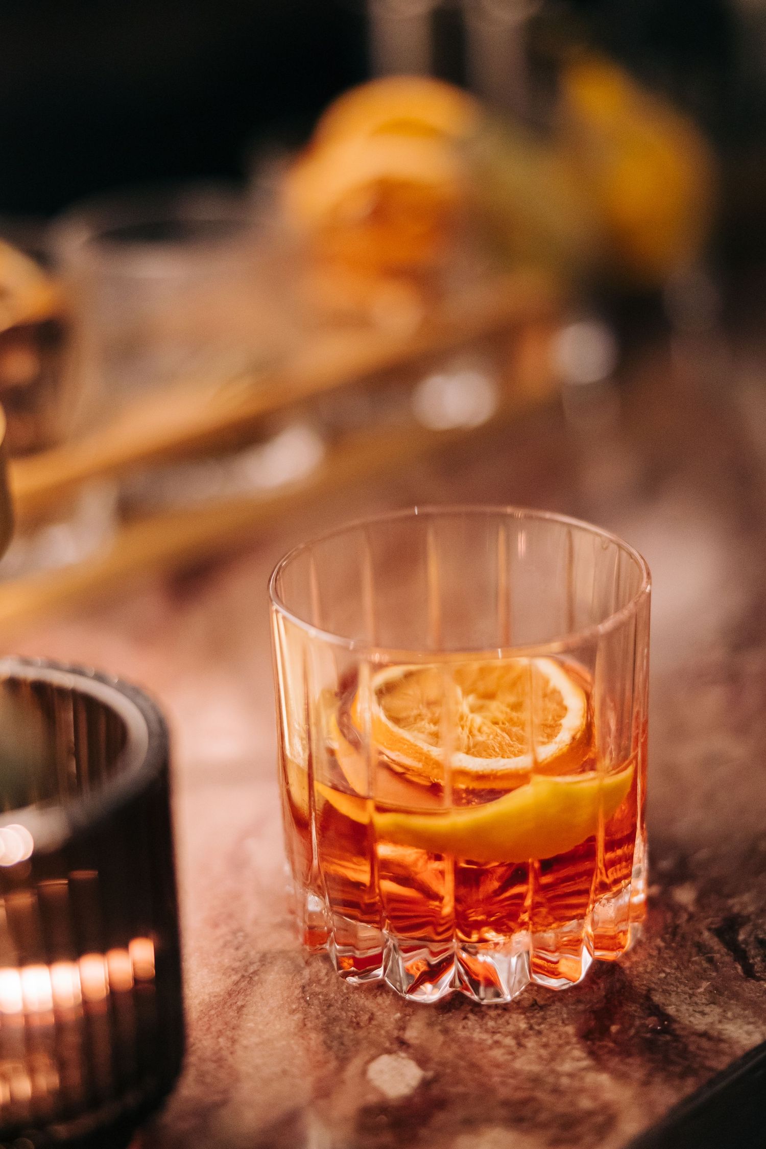 Close-up of a classic cocktail with orange slice garnish in a crystal glass.
