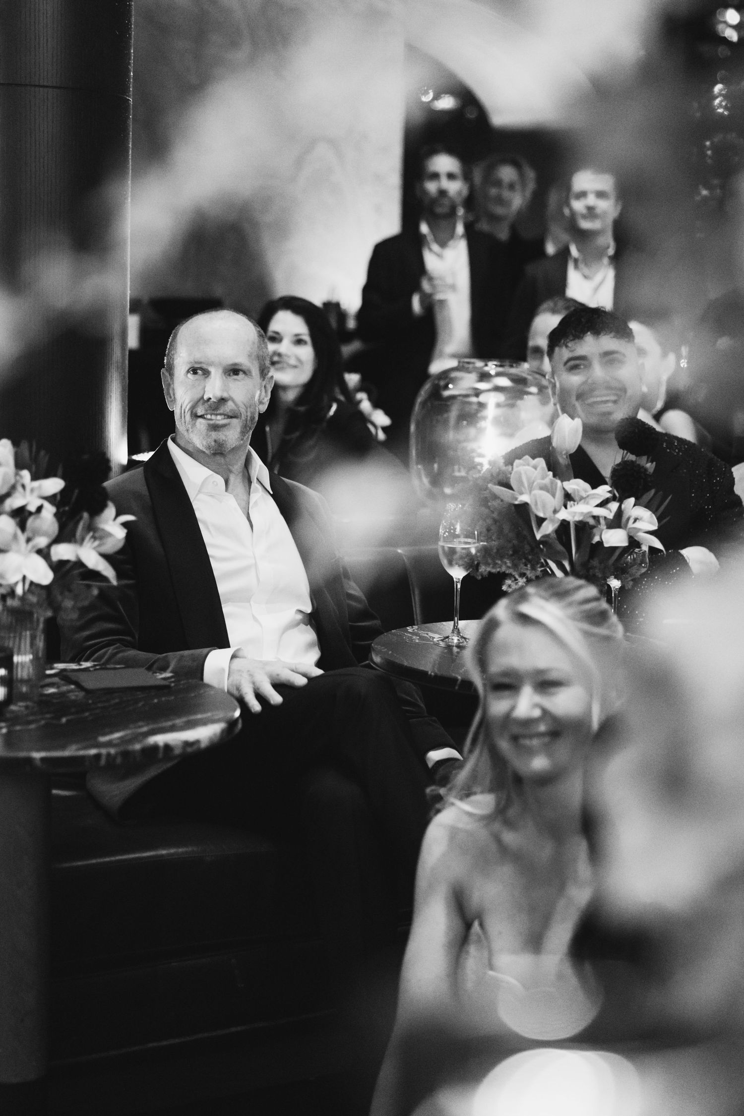Black and white candid shot of wedding reception dinner with decorative table settings.