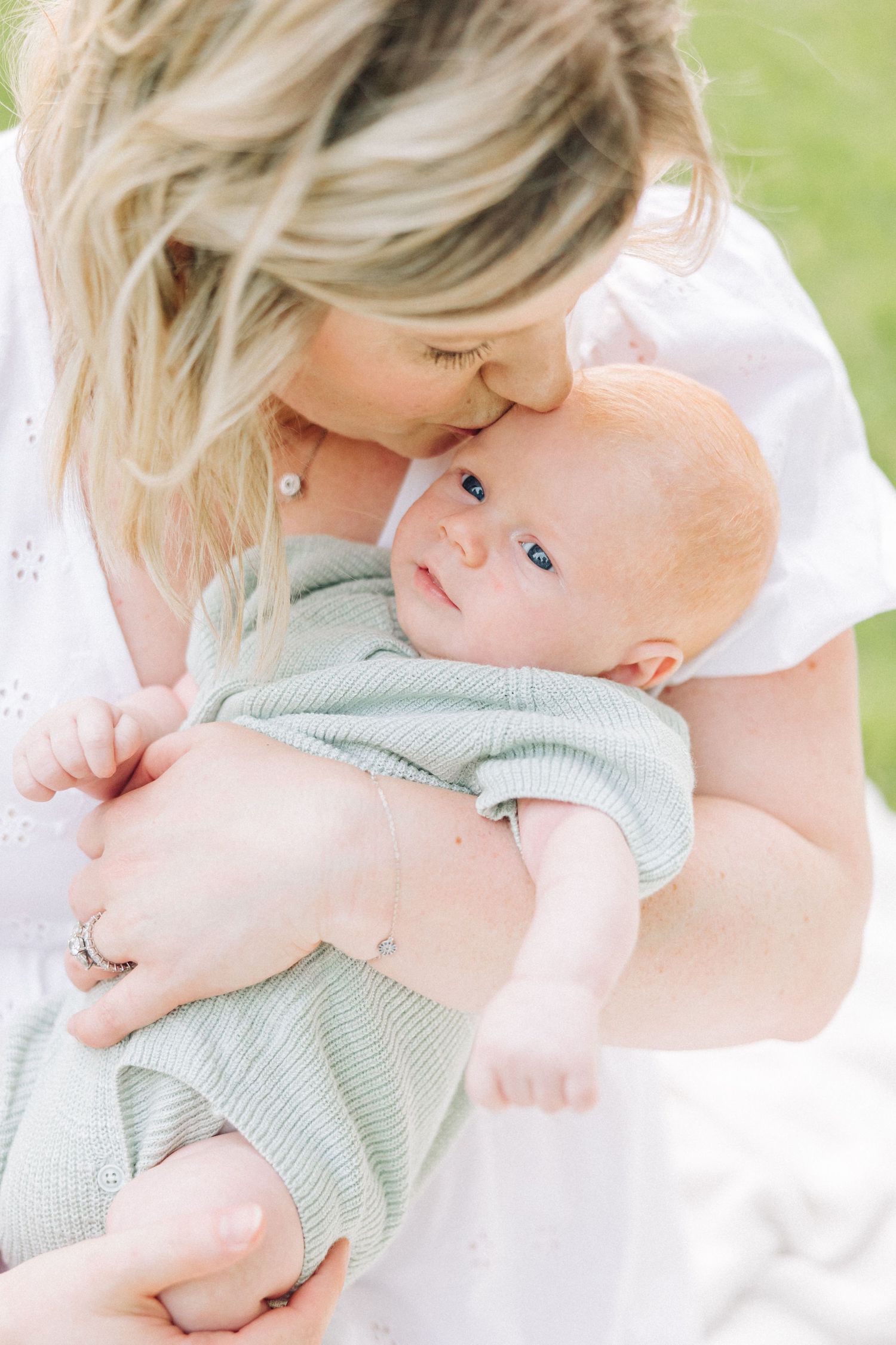 An intimate portrait of a mother snuggling with her baby outdoors.