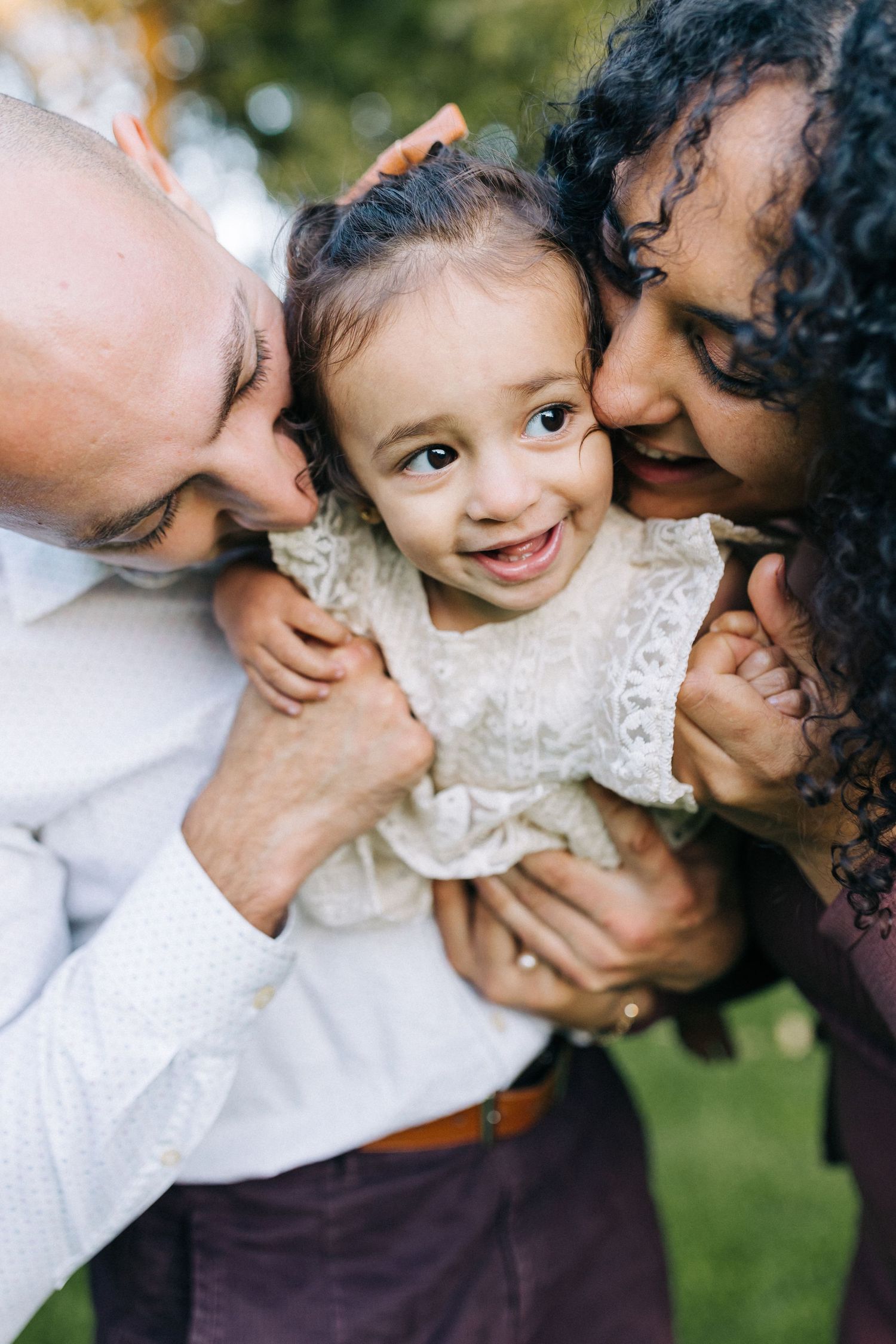 An intimate close-up portrait of parents embracing their young child.