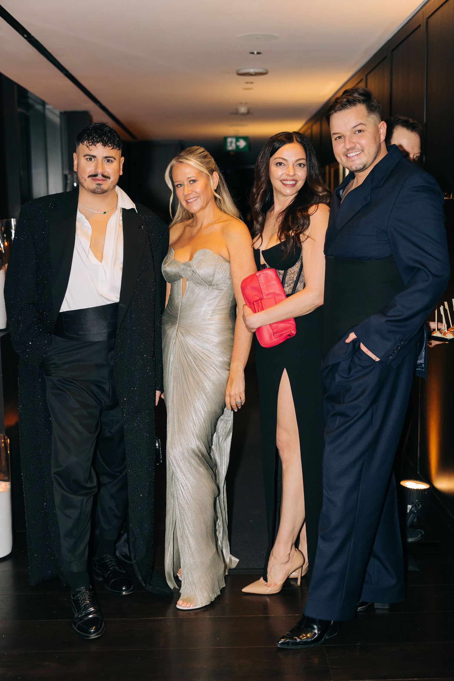 Group of friends dressed in formal attire pose together at an evening event.