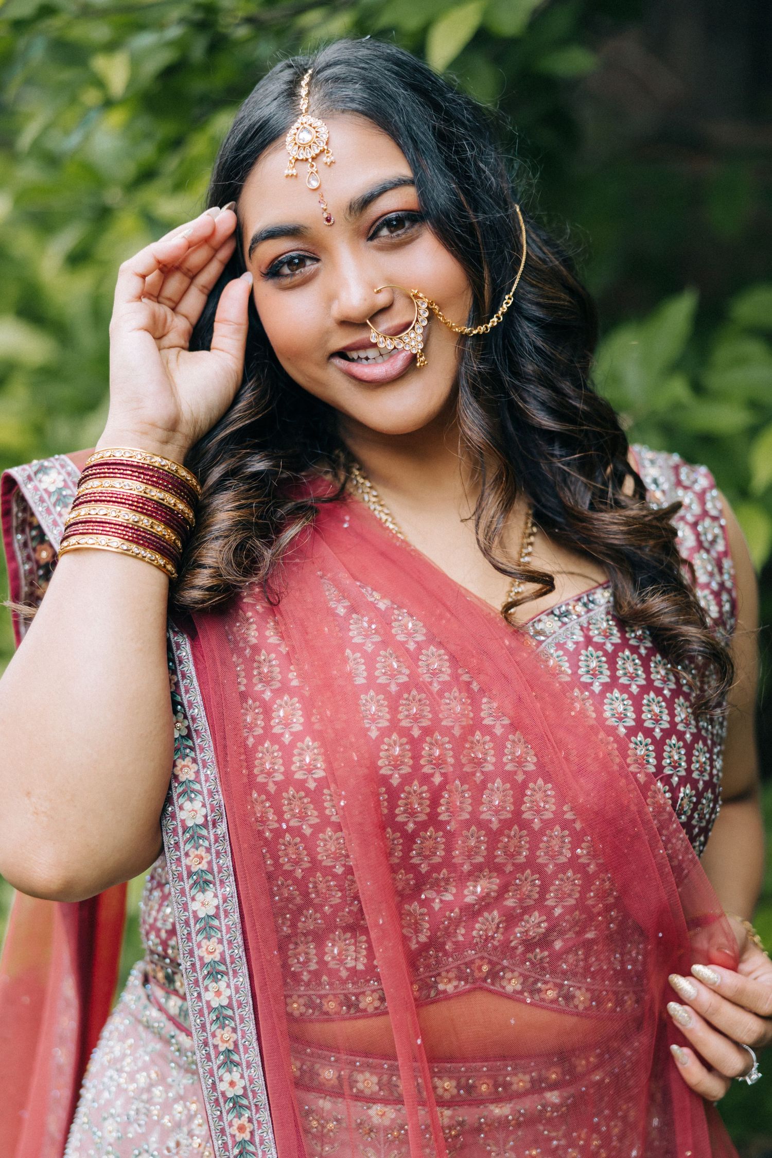 Portrait of bride in traditional Indian wedding attire with jewelry and henna details.