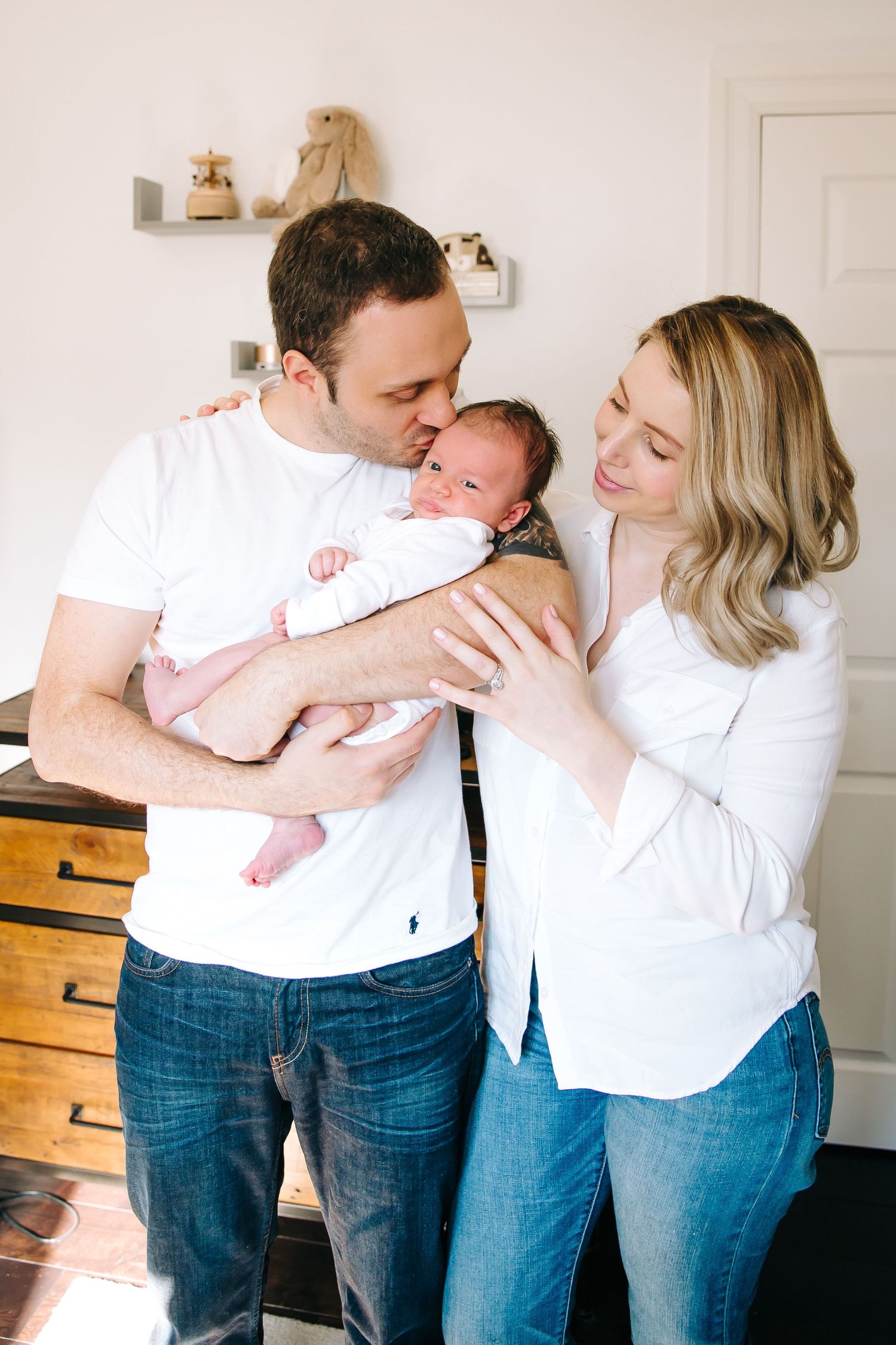 A tender moment between parents and their newborn baby in a nursery setting.