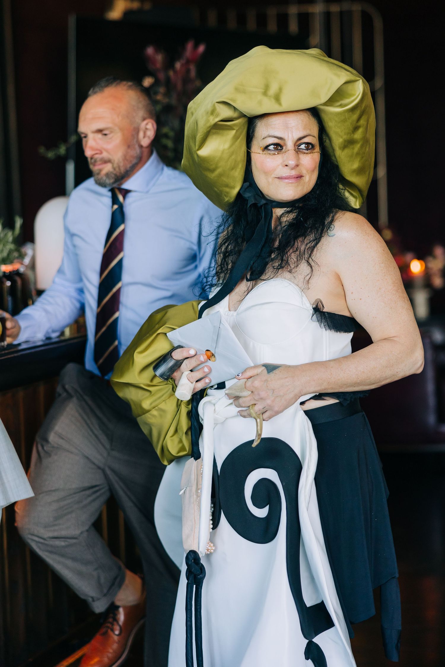 Wedding guests enjoy festivities at a reception with formal attire and playful green accessories at indoor venue.