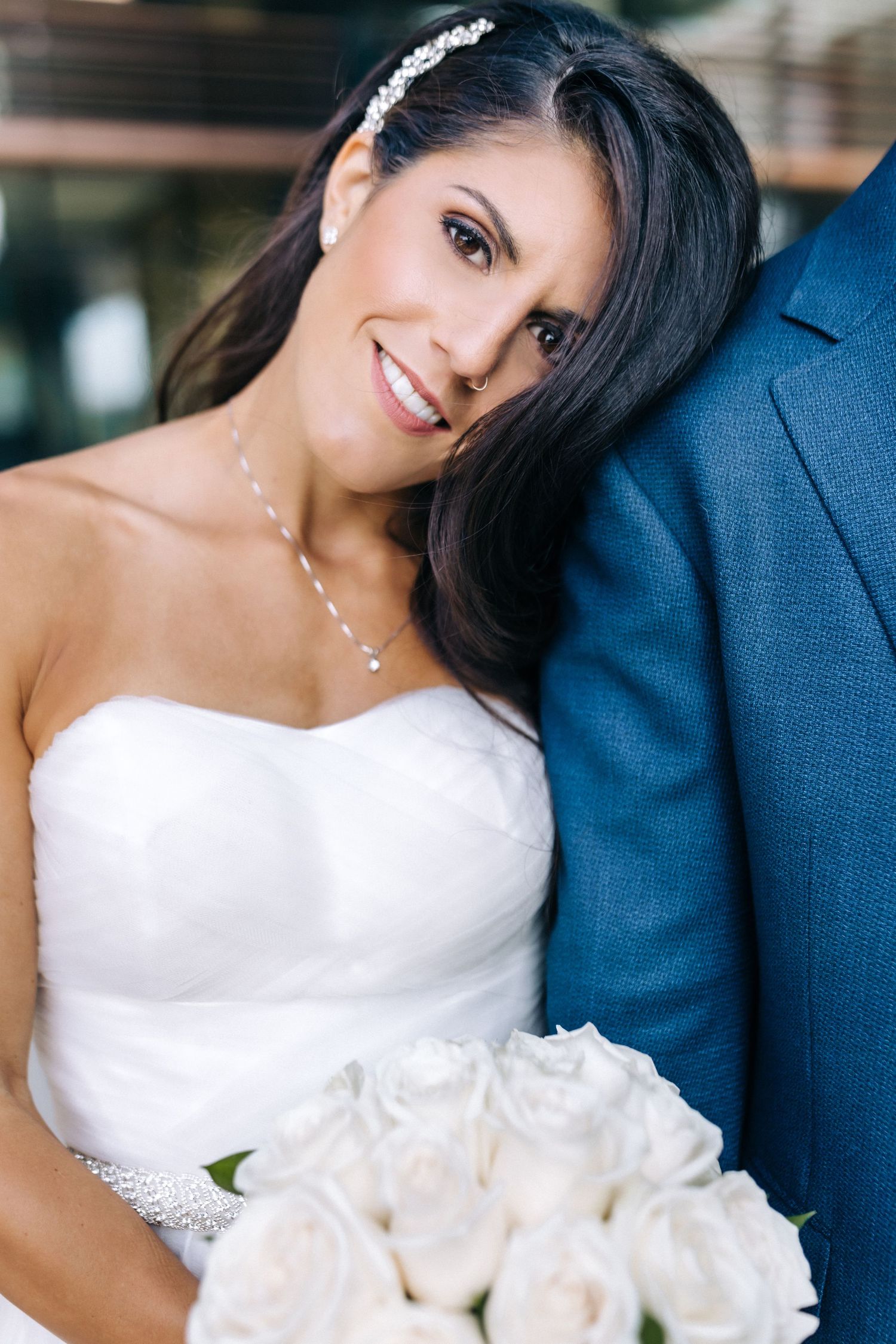 Elegant bride in white strapless dress holds bouquet of roses.