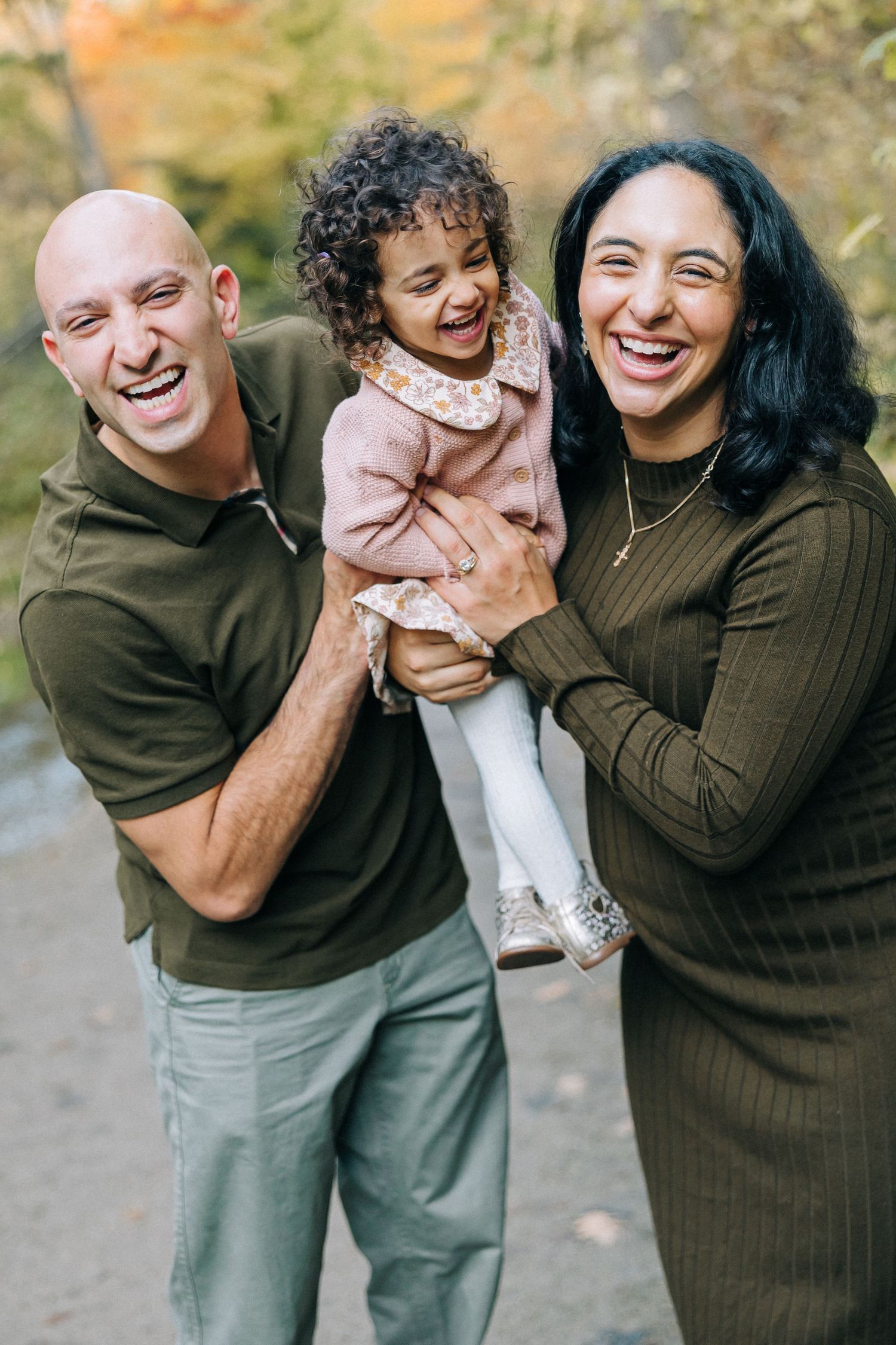 A joyful family sharing laughter together outdoors during an autumn photoshoot.