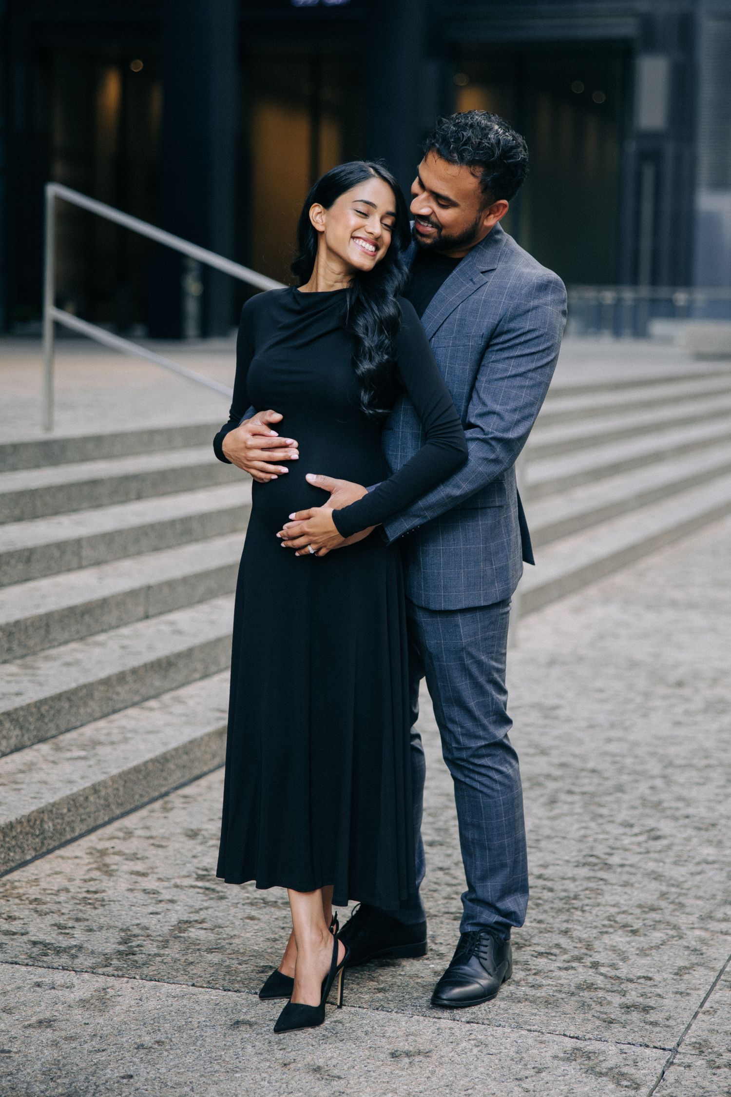 Loving couple shares intimate moment on urban steps in formal attire.