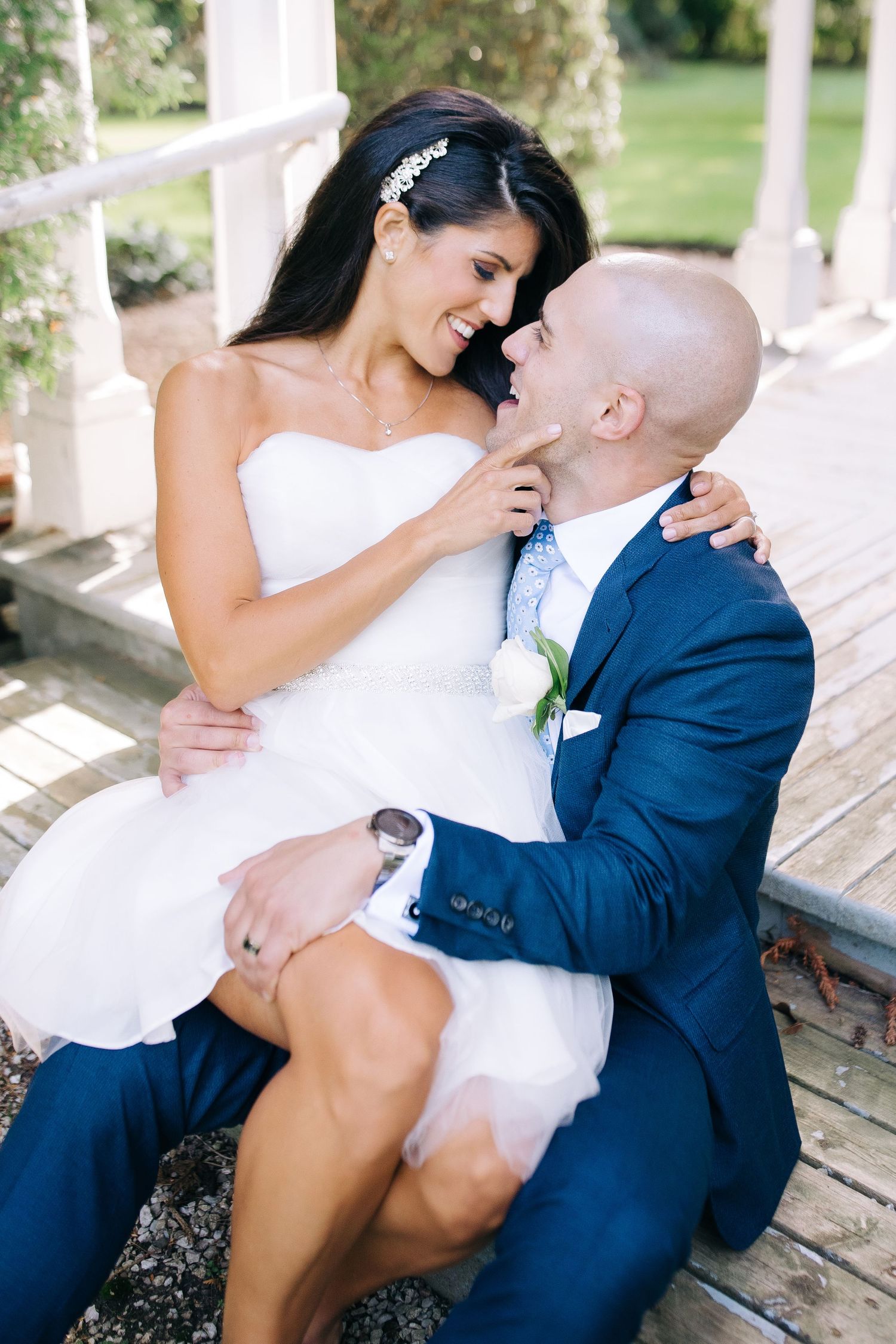 Romantic wedding couple shares an intimate moment while sitting on a rustic porch in natural lighting.