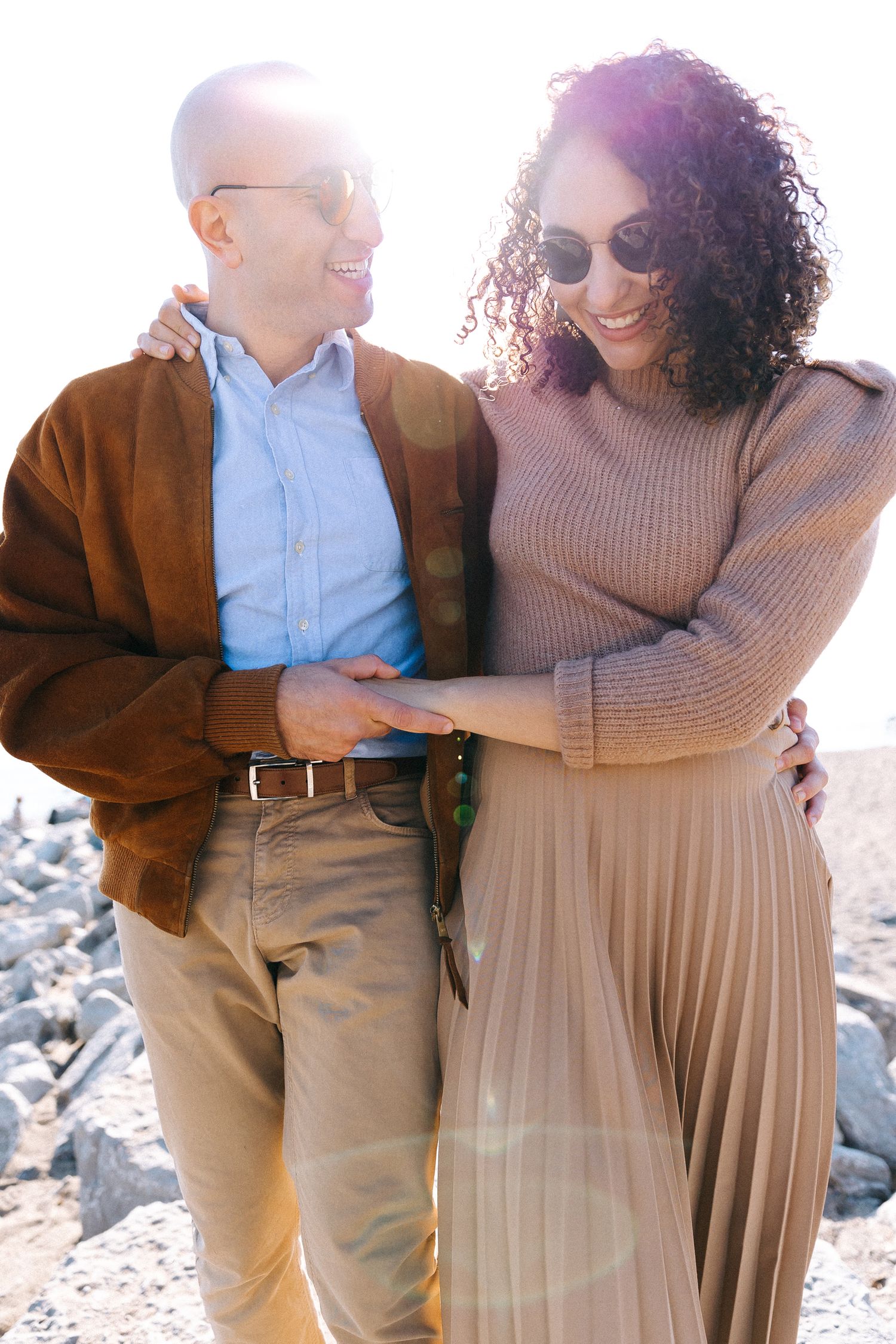 A couple in casual outfits share a moment together in warm sunlight.