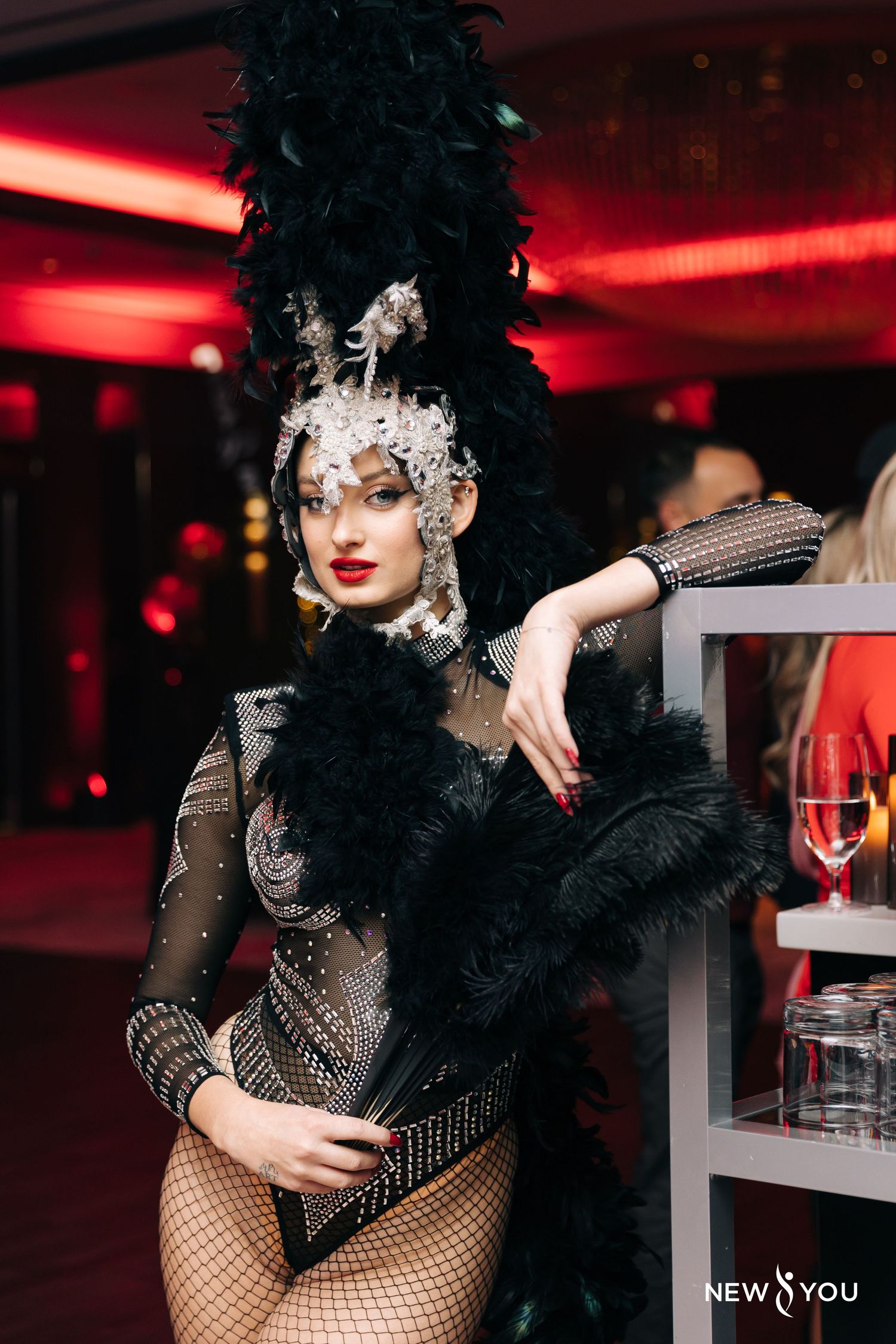 Showgirl in elaborate black costume and silver headdress poses dramatically.