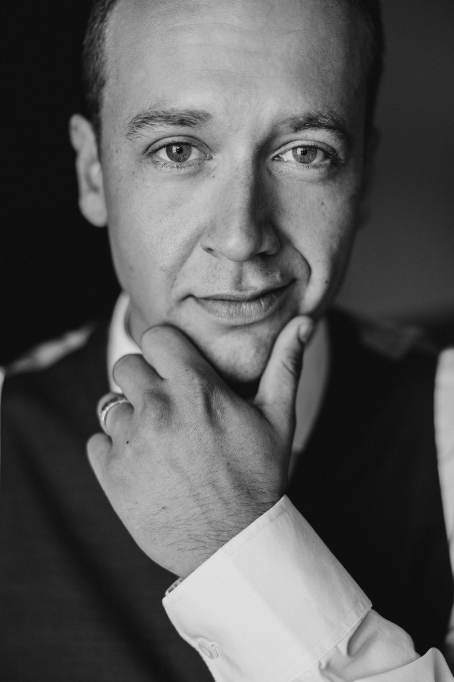 Black and white portrait photograph showing a person in business attire with hand thoughtfully placed under chin.
