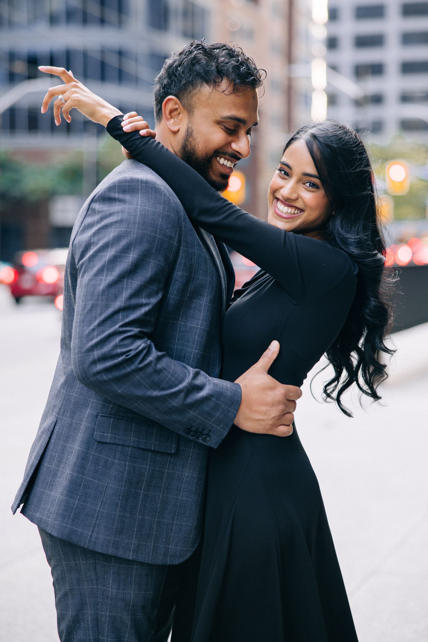 Happy couple embracing and laughing together on urban sidewalk.