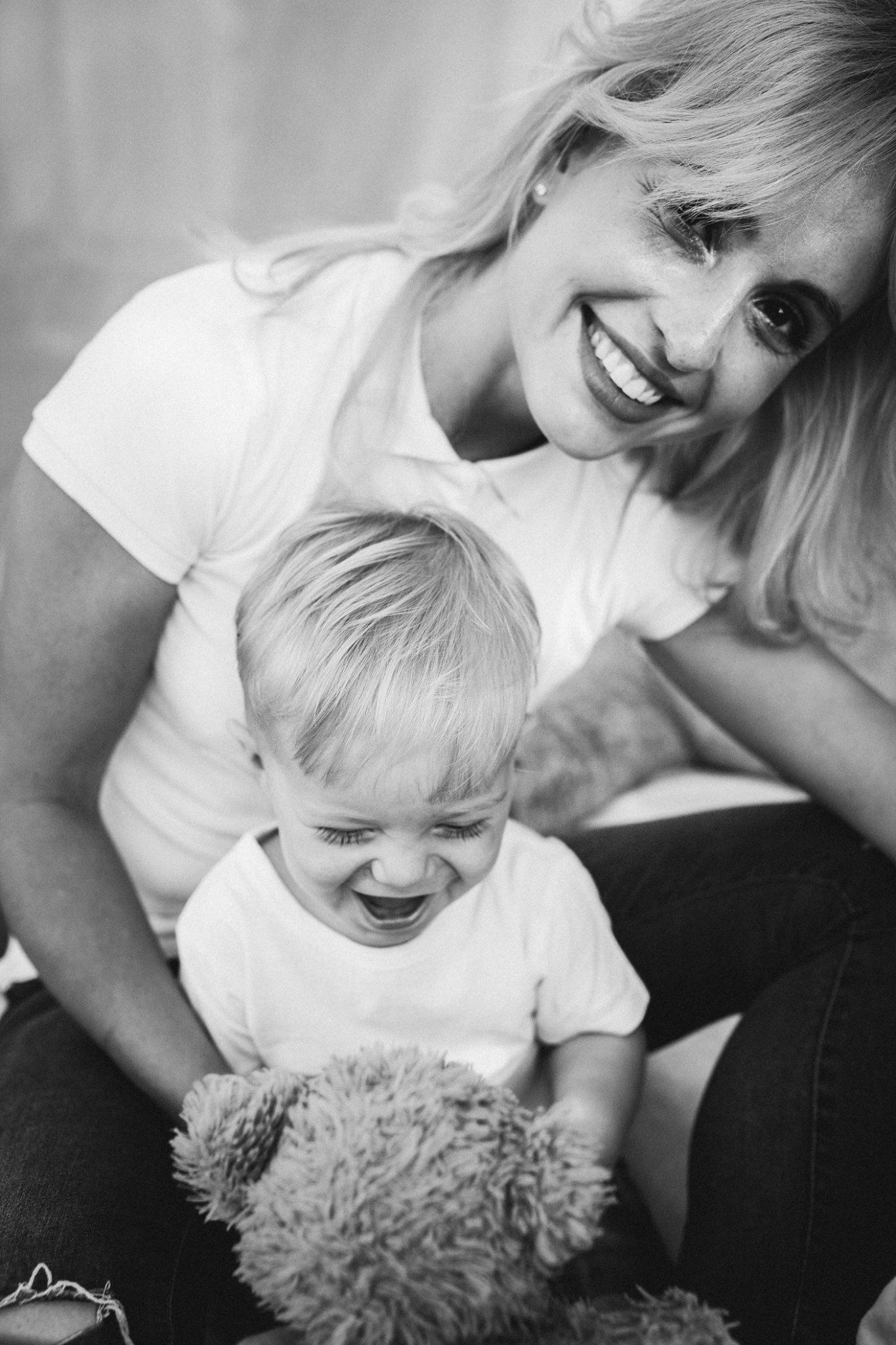 Sweet candid moment with child holding teddy bear in black and white portrait.