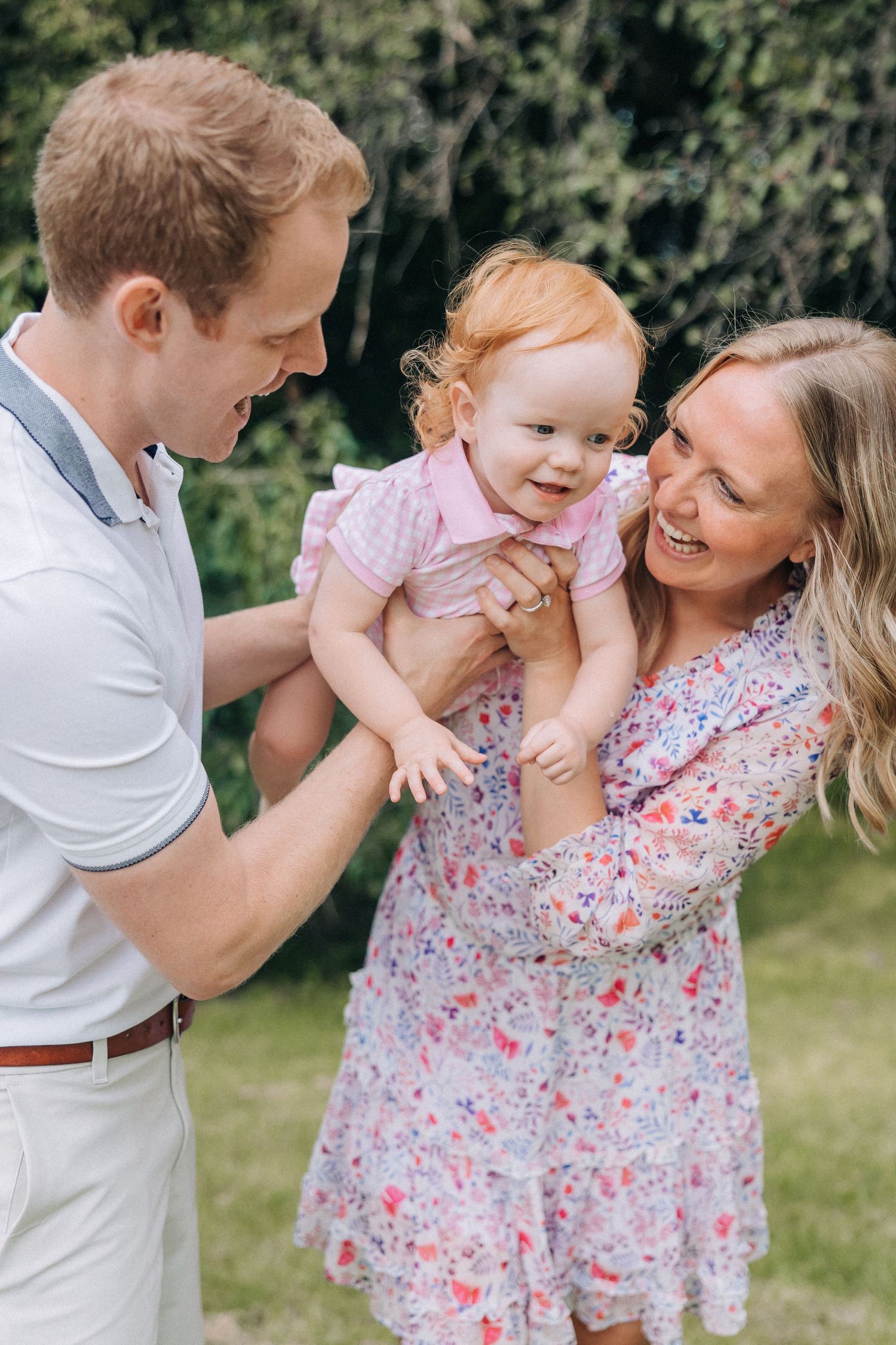 A joyful outdoor family moment with a baby in a pink dress during summer.