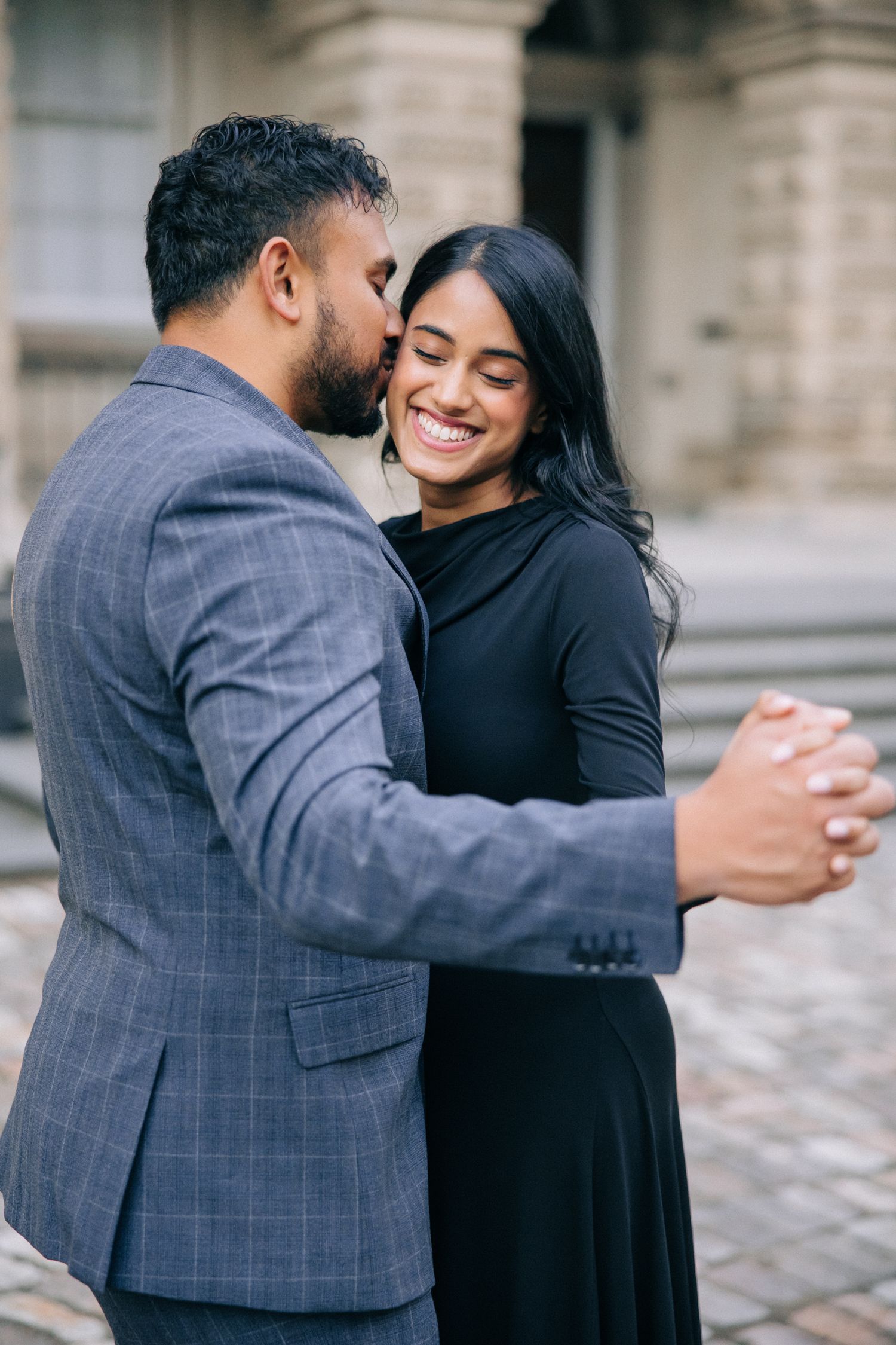 Couple in elegant attire share loving embrace during outdoor photoshoot.