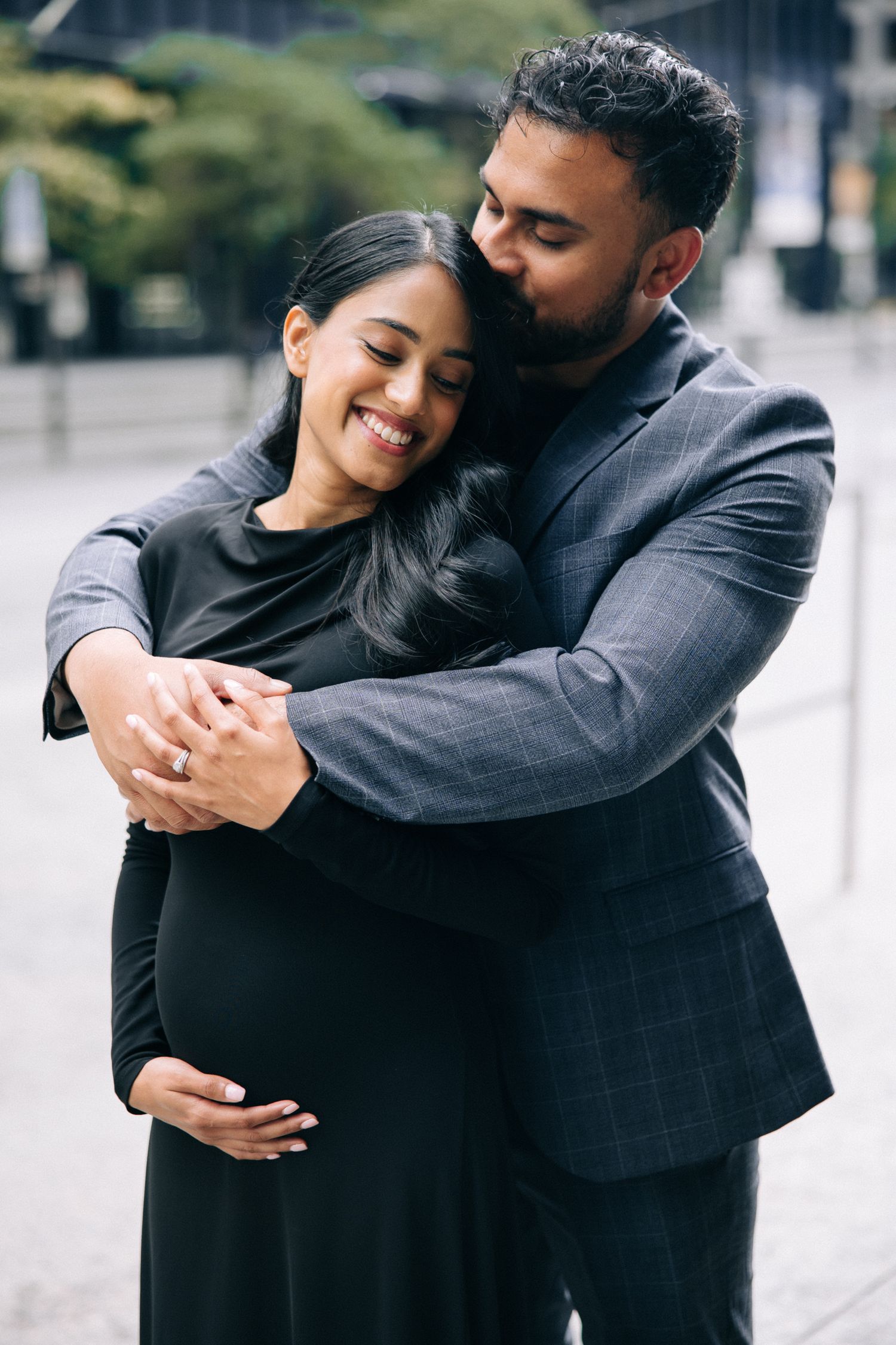 Loving couple embraces outdoors, sharing a tender moment as they celebrate an expected arrival together.