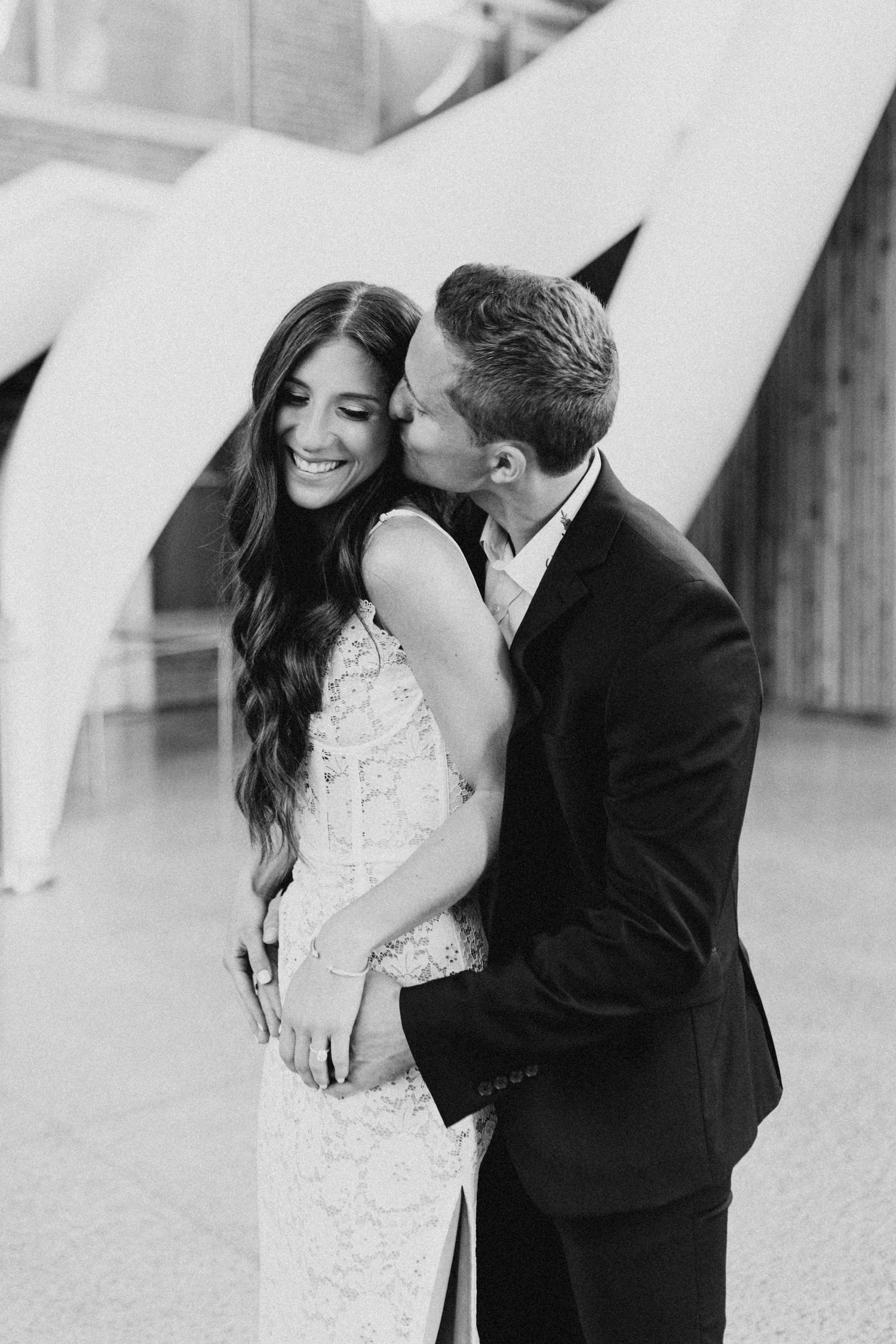 Black and white portrait of couple sharing tender moment in elegant attire.
