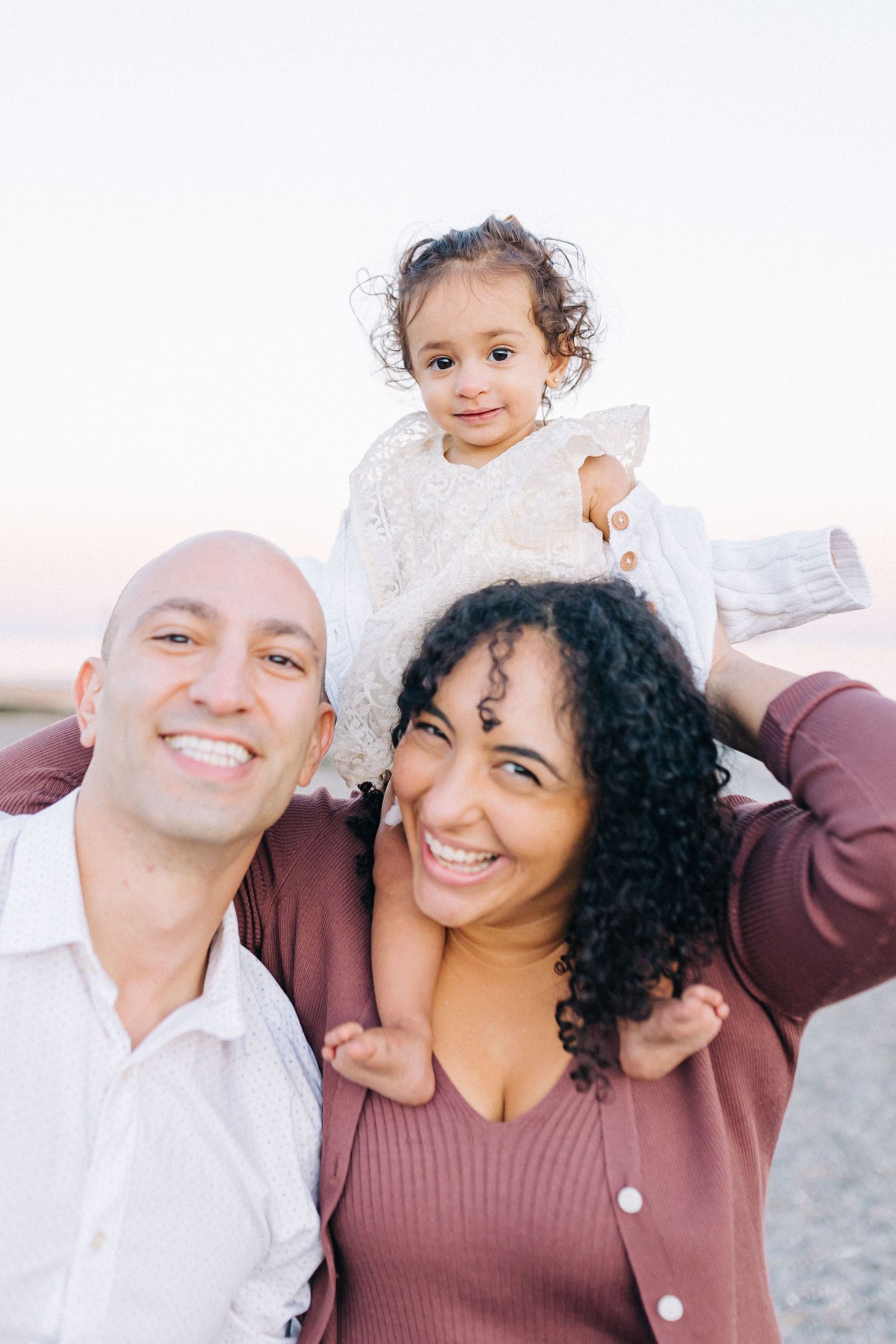 A happy family poses together outdoors during sunset.