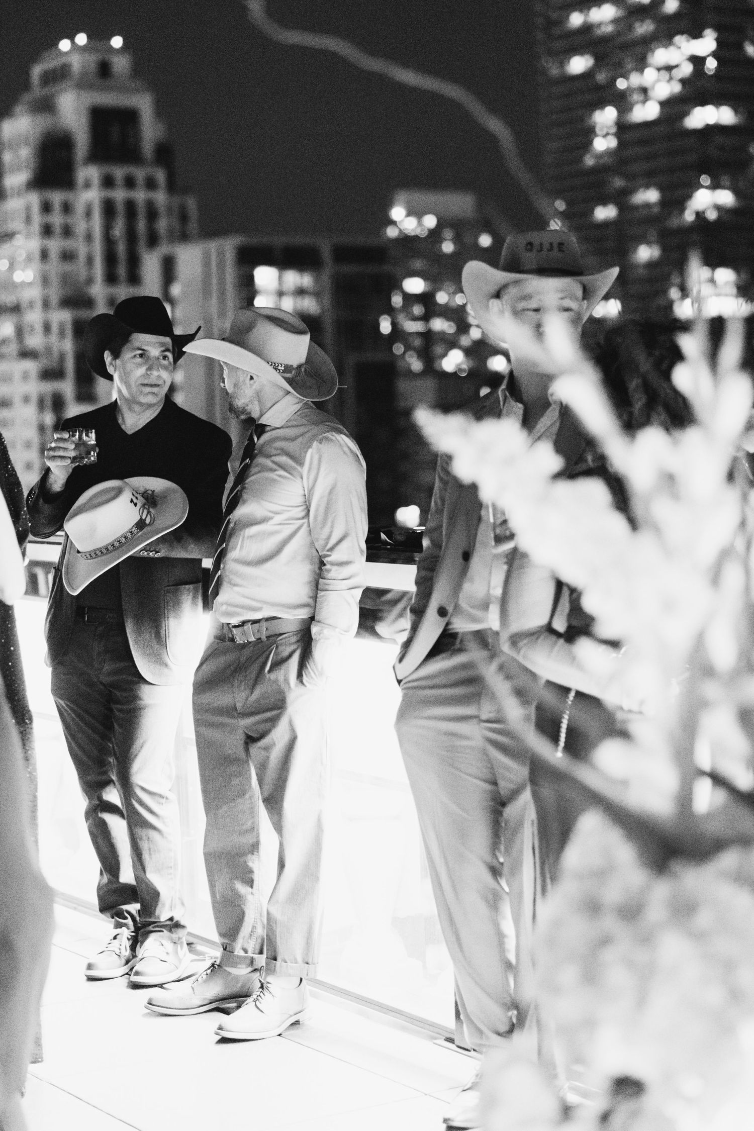 Black and white photo of people gathered outdoors in an urban setting at night.