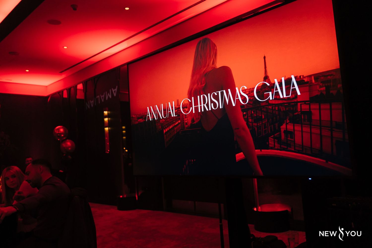 Red-lit event space with silhouettes of people and a 'Christmas Gala' sign display on the wall.