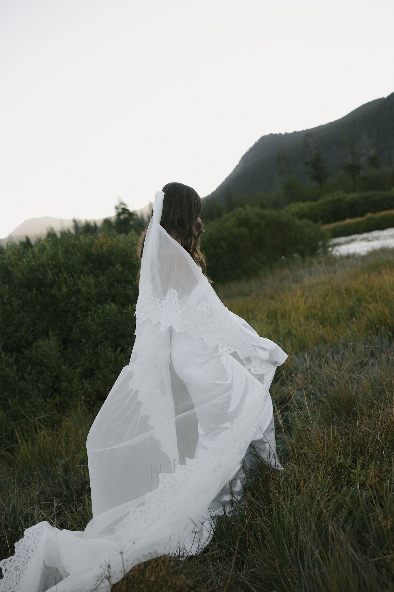 Oregon model, Avery Darling, poses in a wedding dress and a long veil as she walks through a grassy field.