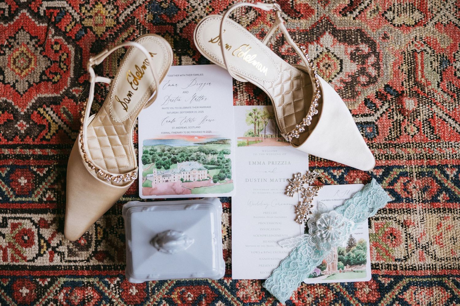 Wedding invitation suite displayed on an ornate patterned rug with vintage styling elements.