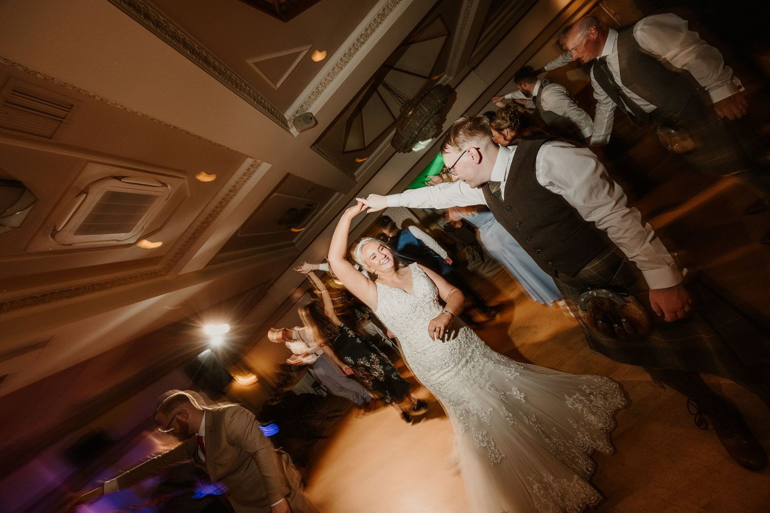 People dancing together on a dance floor at a wedding reception with dramatic lighting and decor.