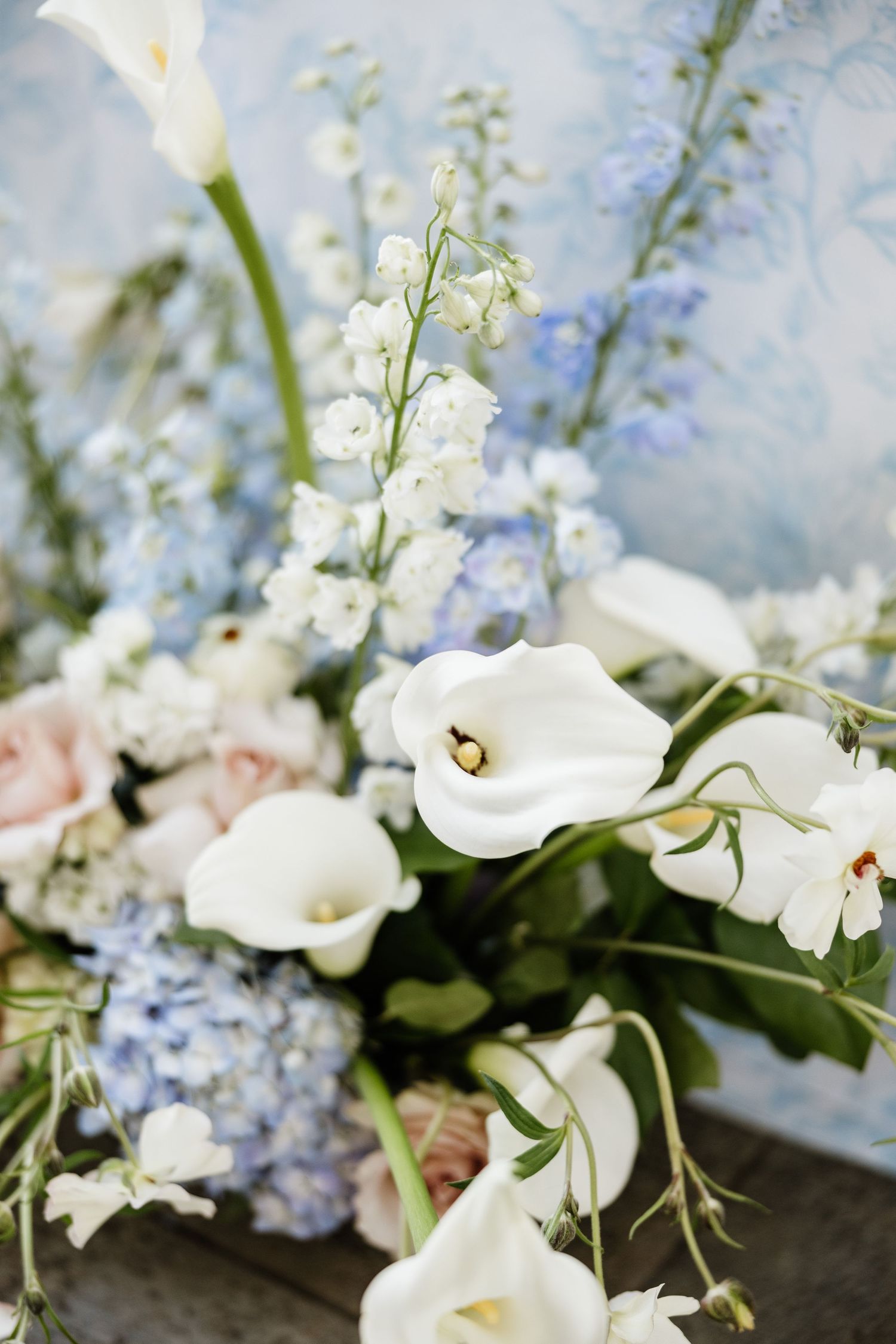 Close-up of delicate white calla lilies, hydrangeas and blush roses in a romantic floral arrangement.