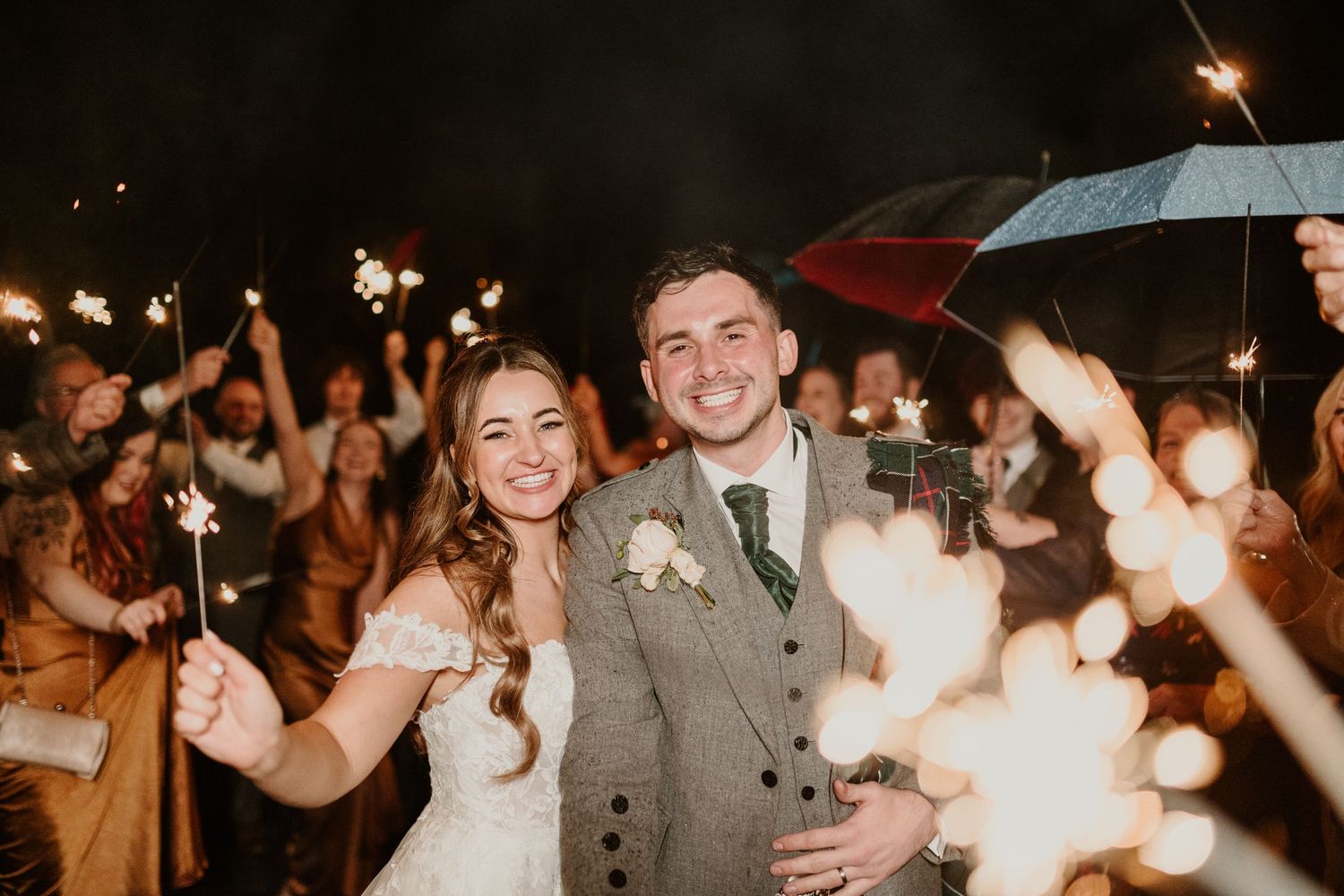 Sparkler exit celebration at night with wedding guests holding lit sparklers outdoors.