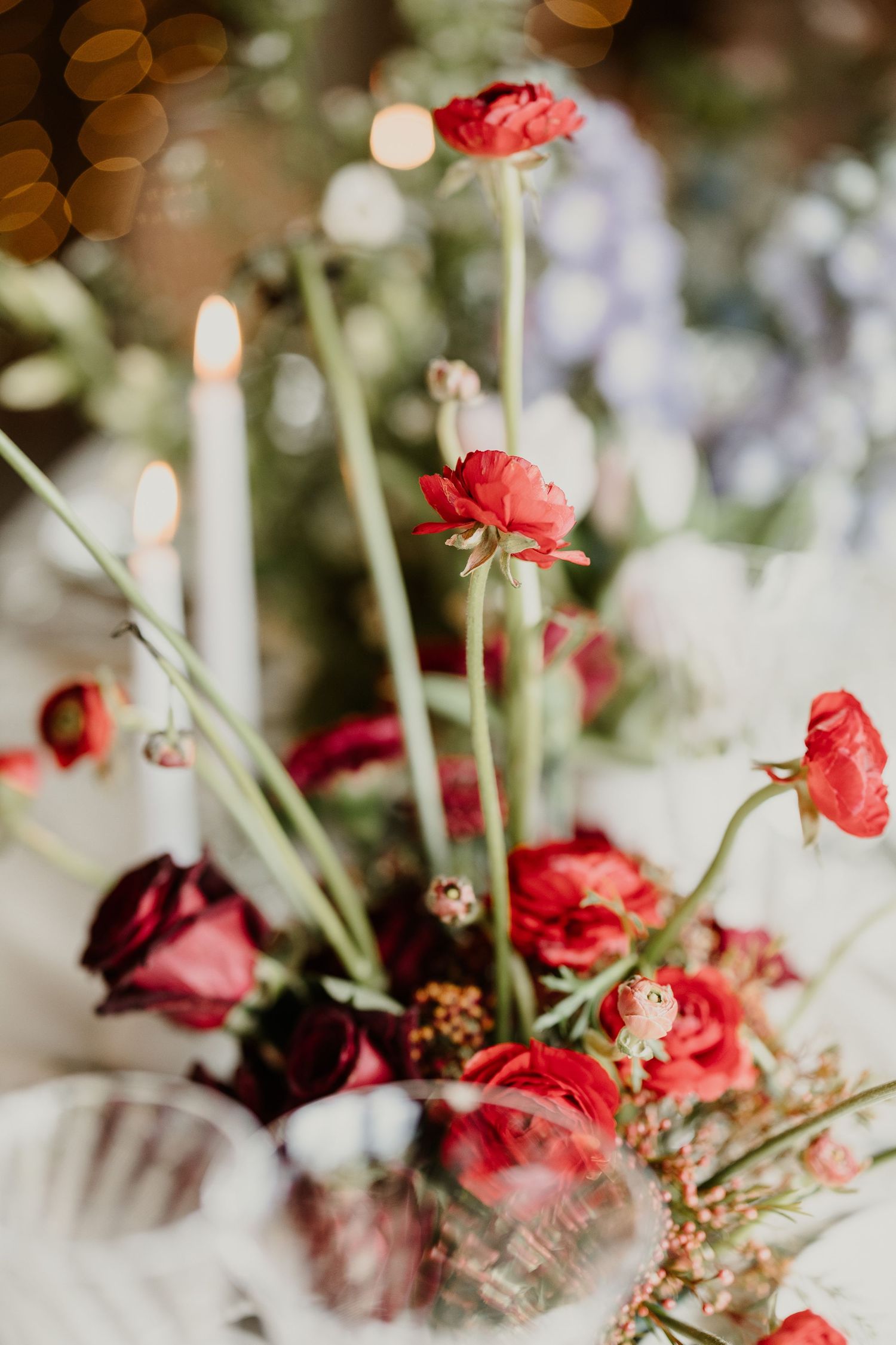 Dreamy centerpiece of red ranunculus flowers in soft focus with bokeh lights.
