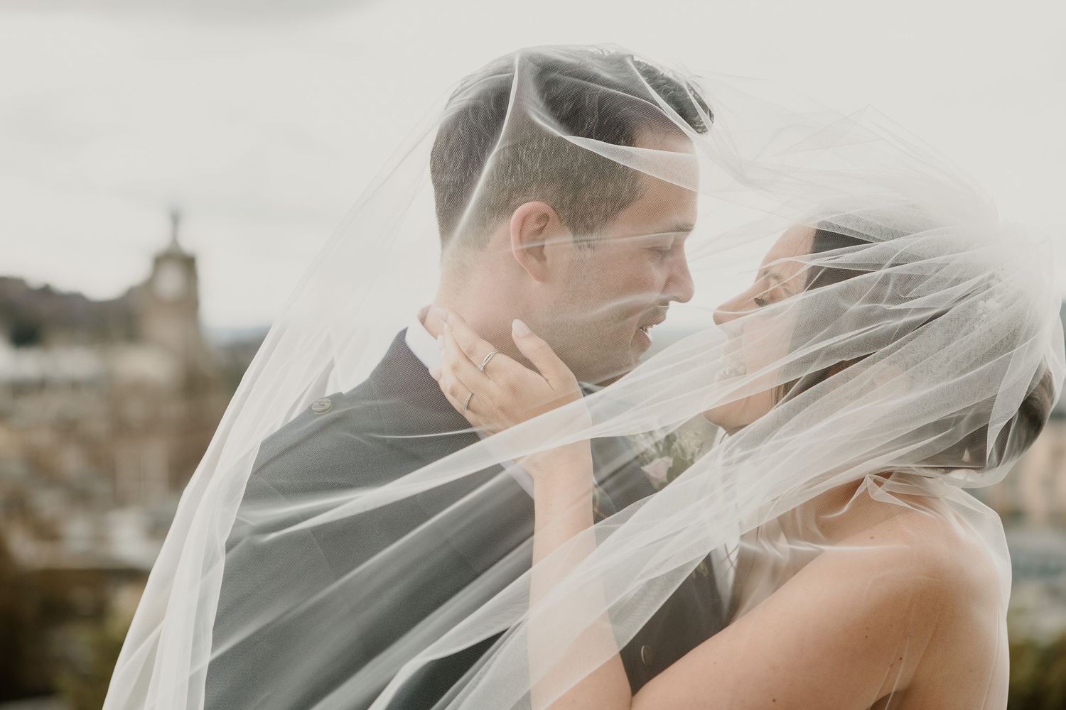 A romantic wedding couple share an intimate moment as the bride's veil flows in the wind.