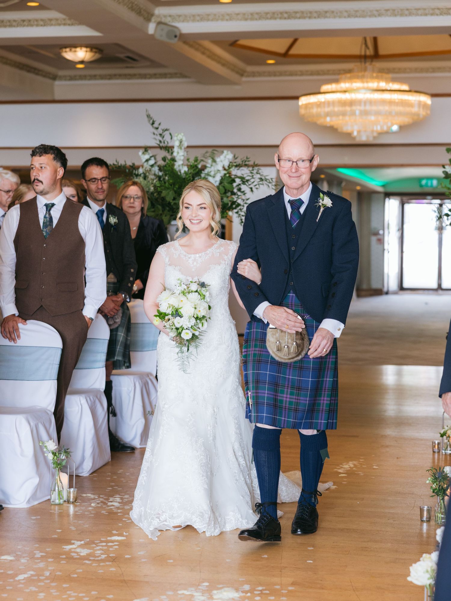 Dancing couples celebrating at an elegant ballroom wedding reception with chandeliers and decorative lighting.