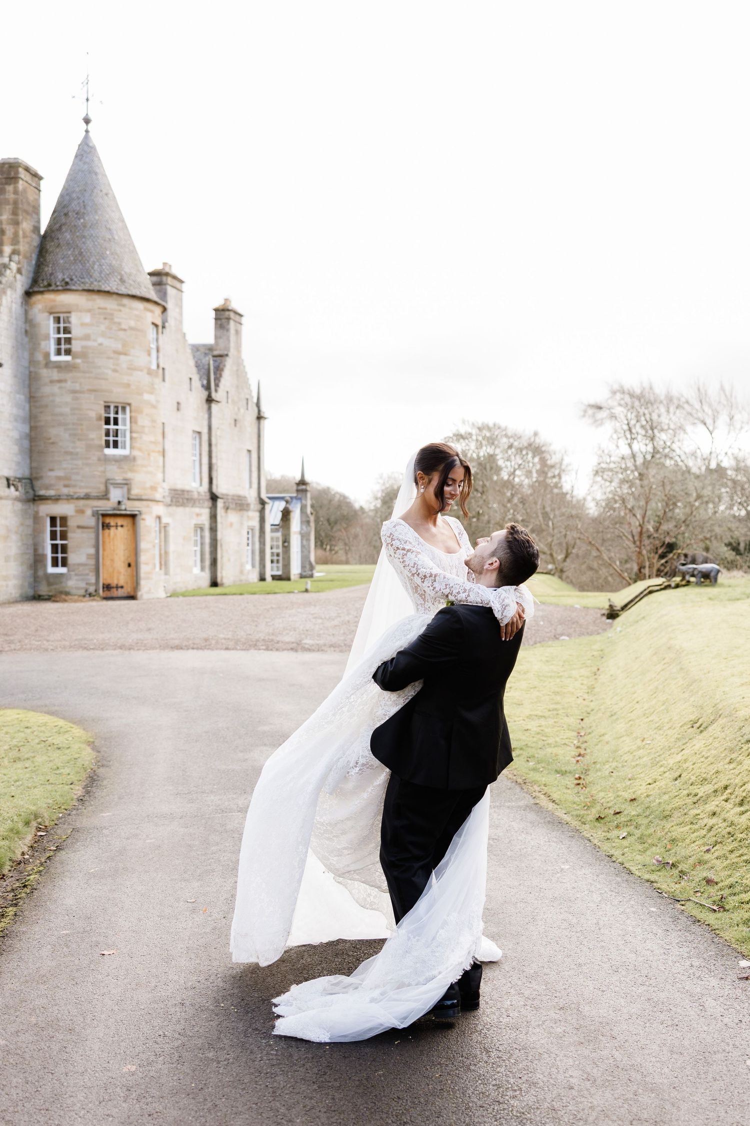 Romantic wedding couple dancing outside a majestic stone castle in Scotland.
