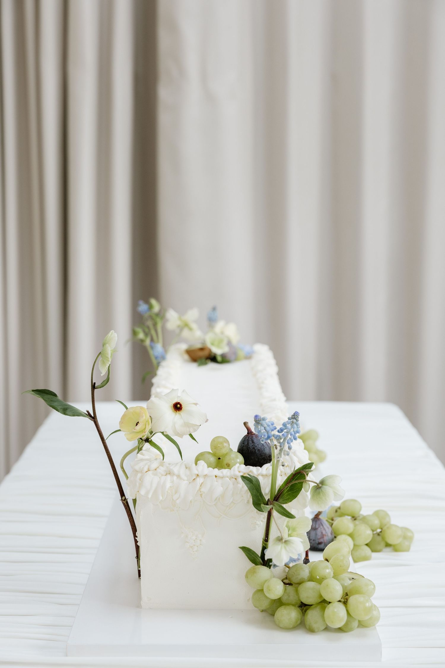 Elegant wedding reception table settings with fresh grapes, delicate white flowers and soft draping fabric.