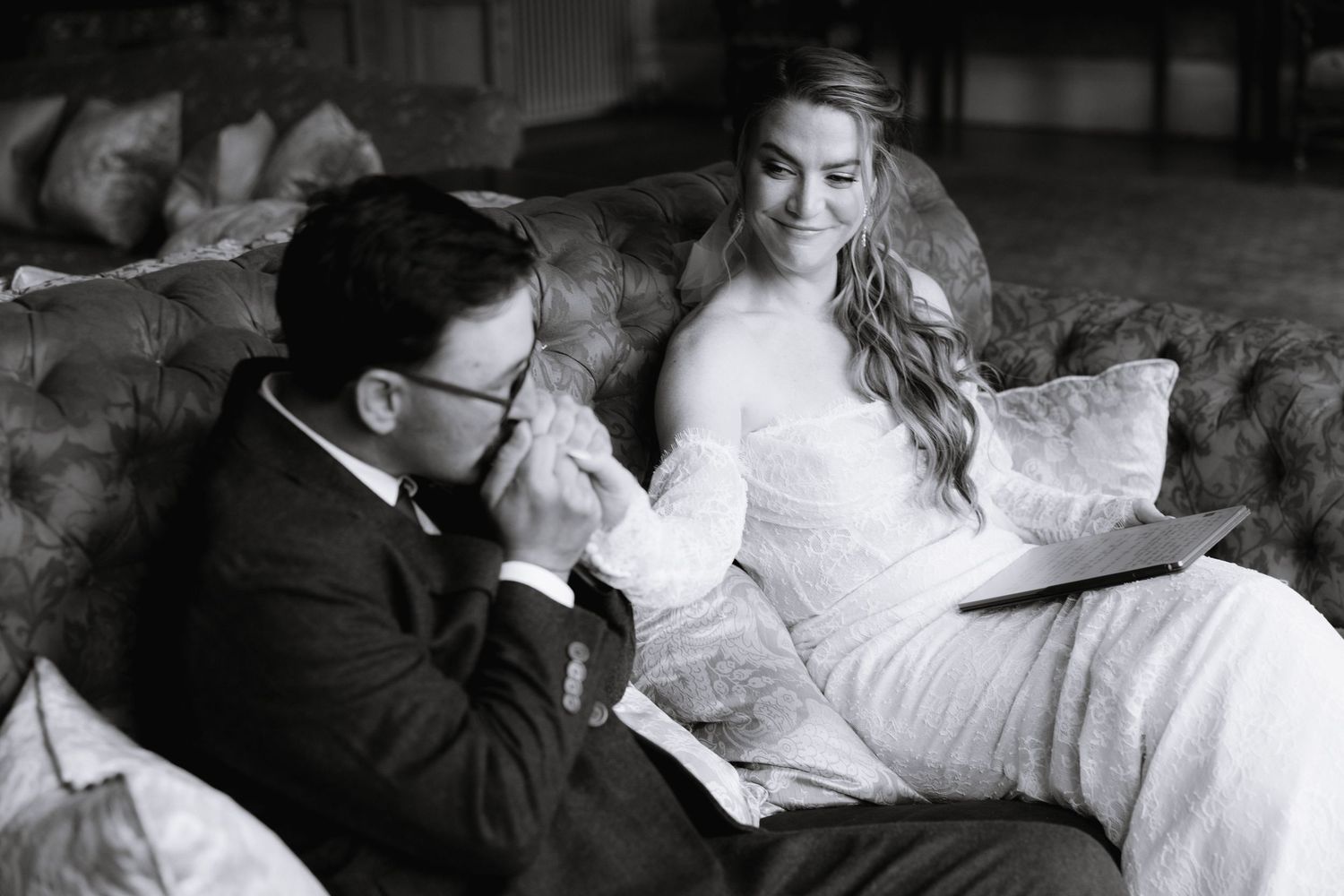 A romantic black and white photo of a couple sharing an intimate moment on a couch.