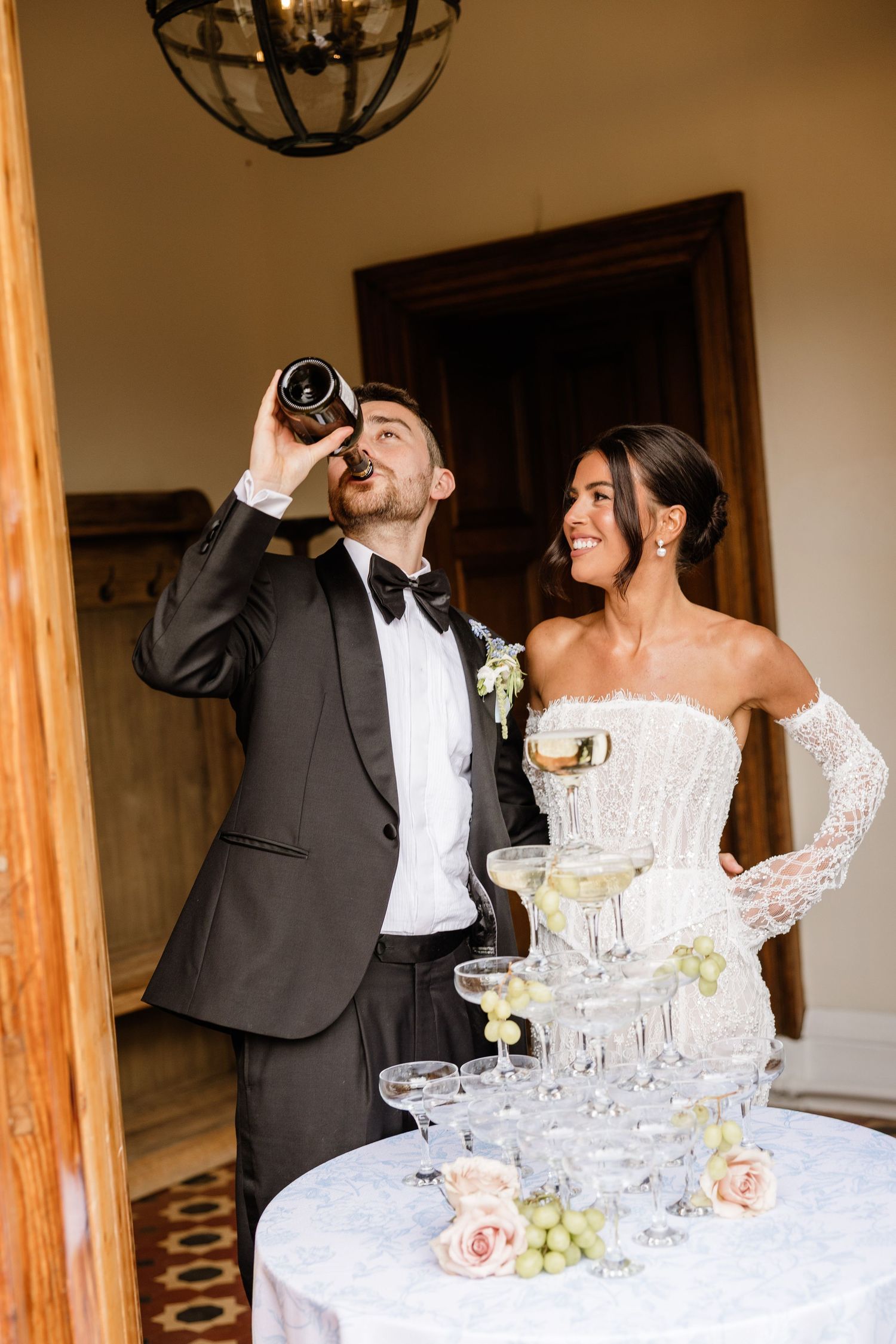 A couple celebrates at their wedding reception with champagne tower and elegant floral decorations.