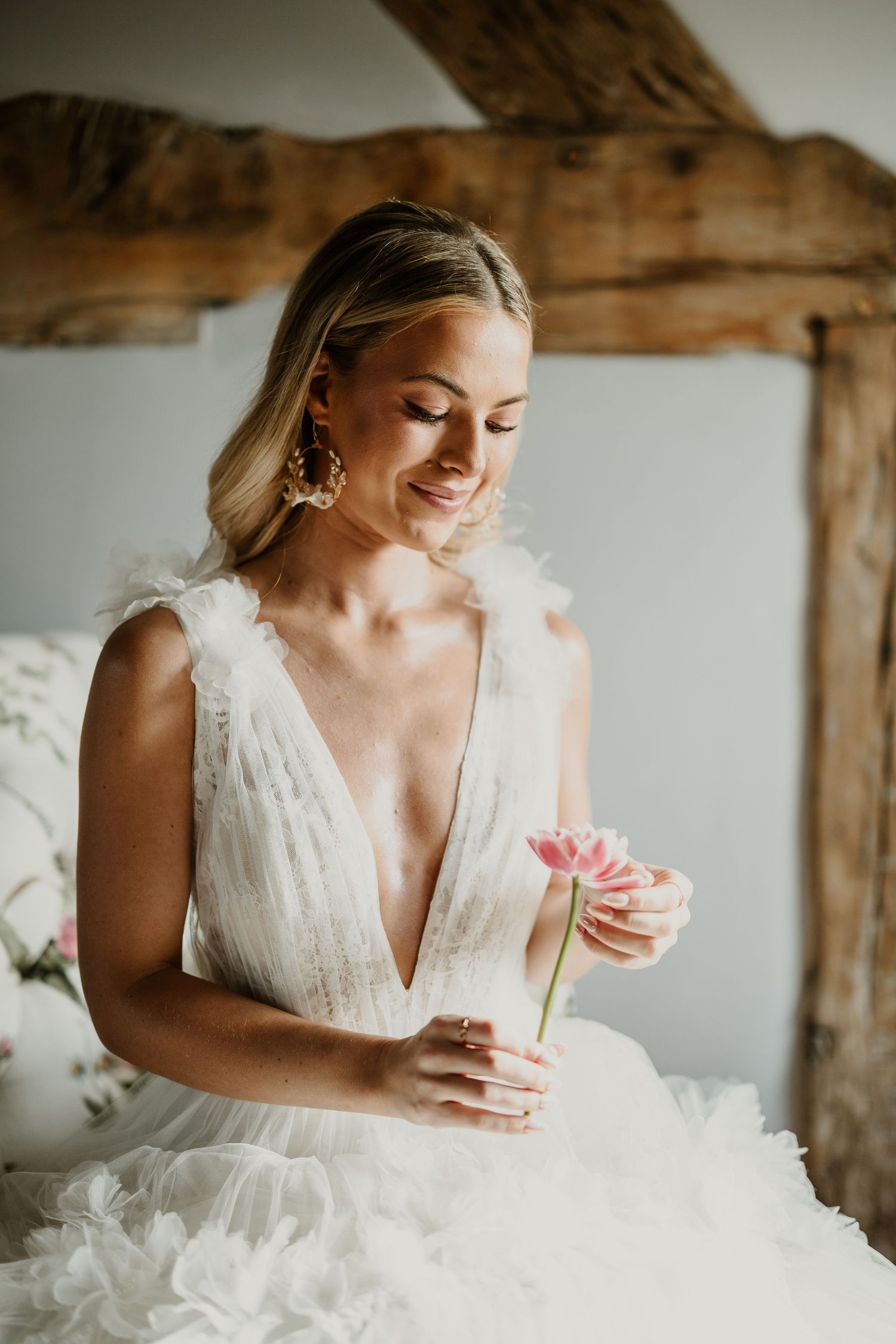 Ethereal bridal portrait in a flowing white gown with rustic wooden beam detail.