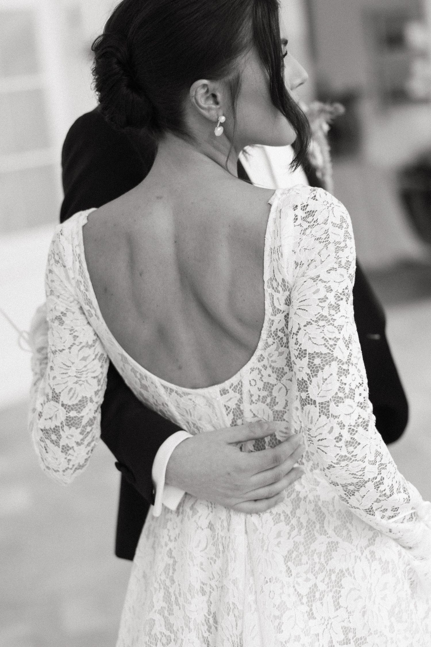 Close-up view of delicate white lace details on the back of a wedding dress with buttons and scalloped edges.